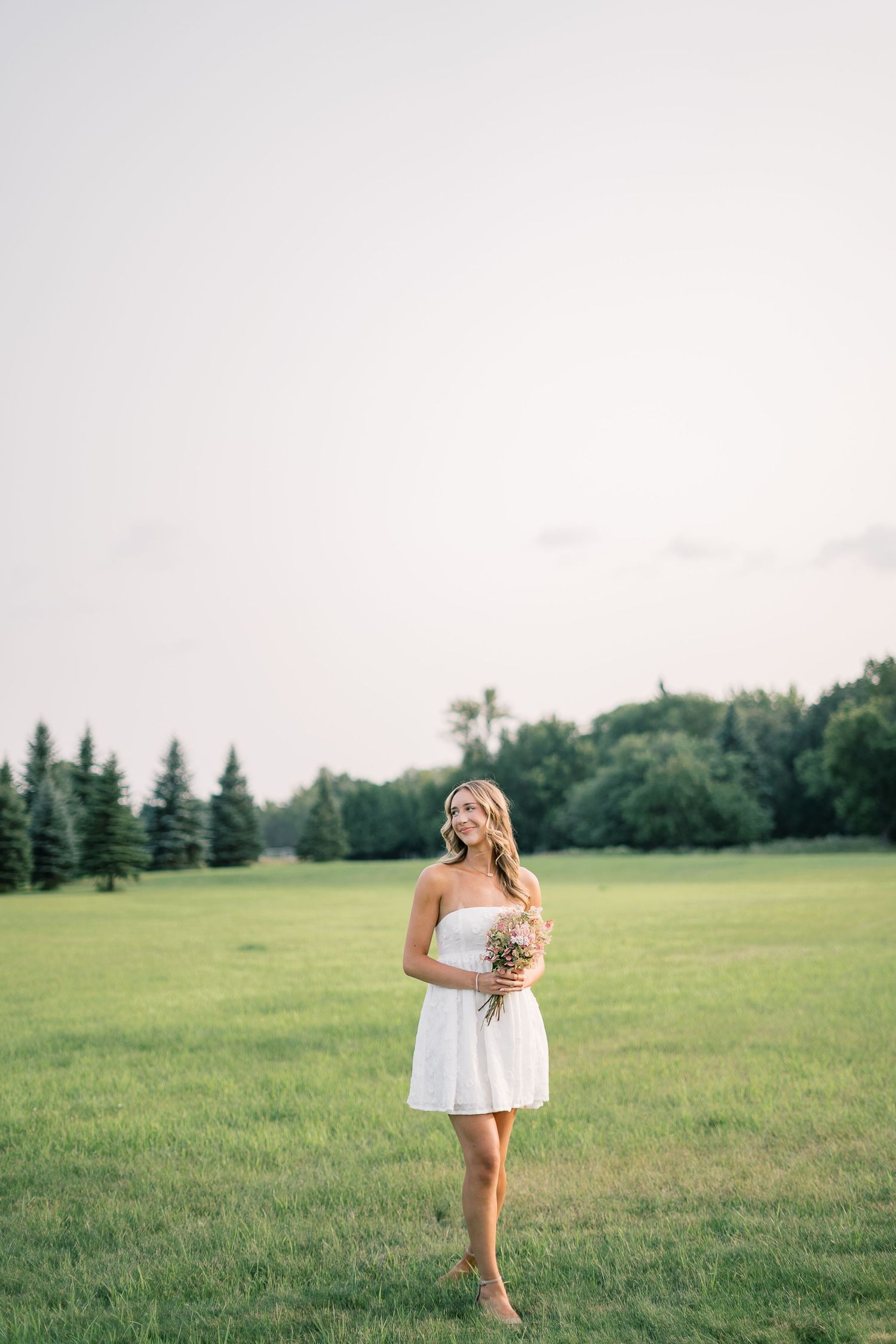 A figure in a white dress runs through a serene green meadow on a summer day.