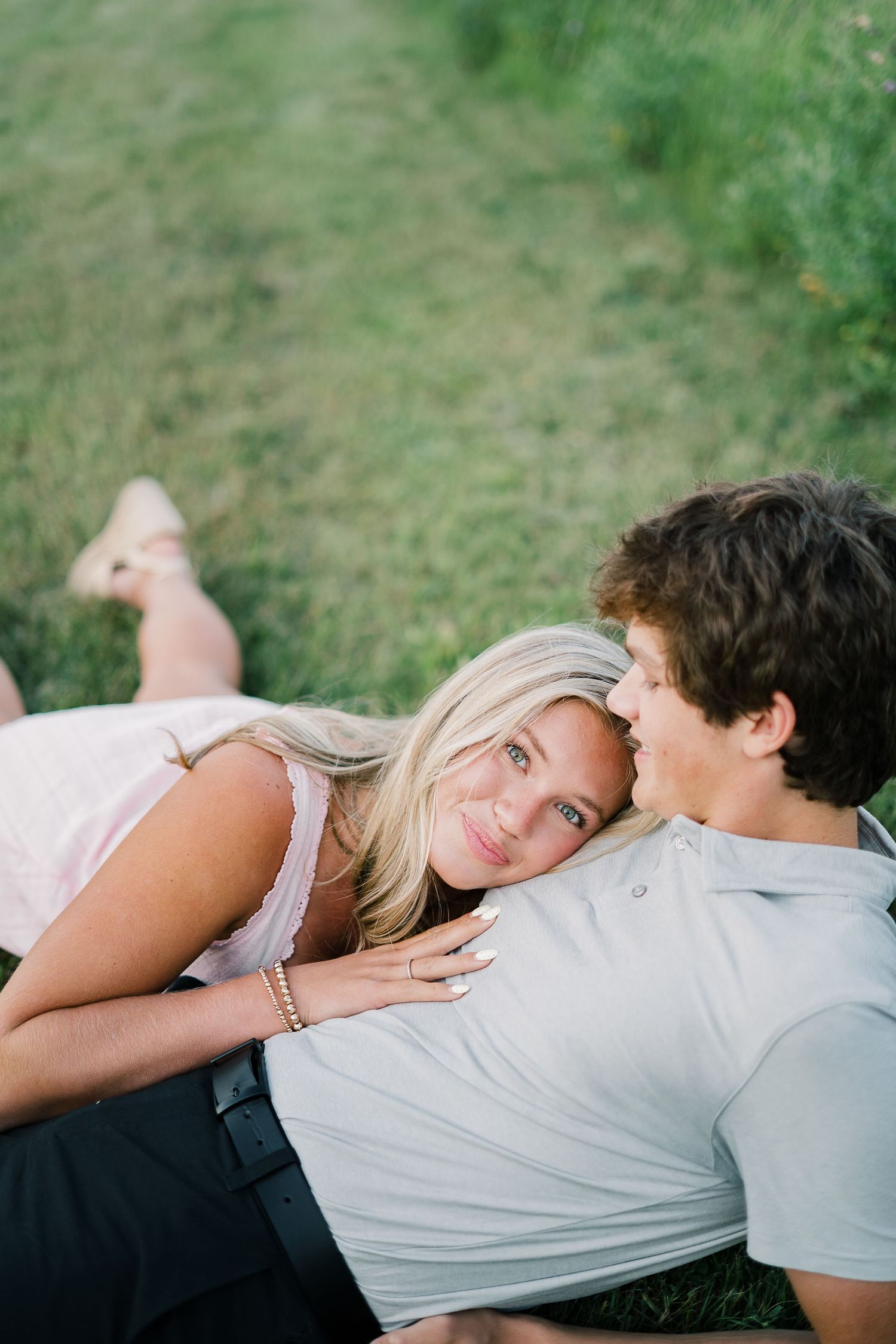 A couple lying down together on grass having an intimate moment outdoors.