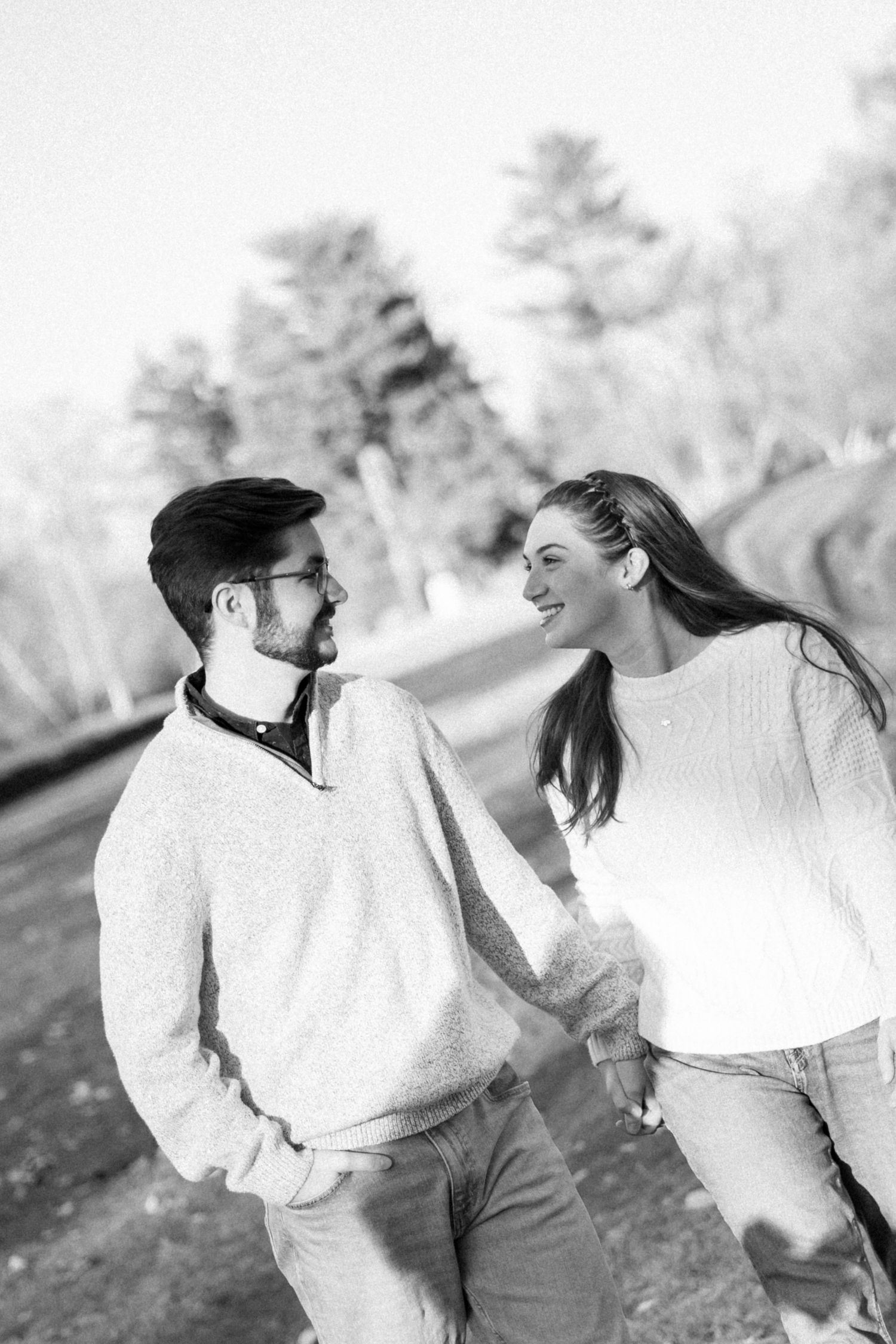 A couple in white sweaters share joyful moments together in a black and white photo sequence outdoors.