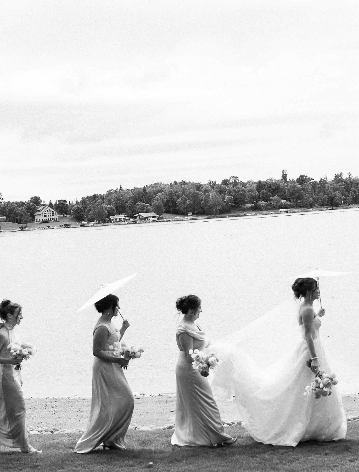 A panoramic black and white photo shows people sitting in a row on a beach, creating an artistic silhouette effect.