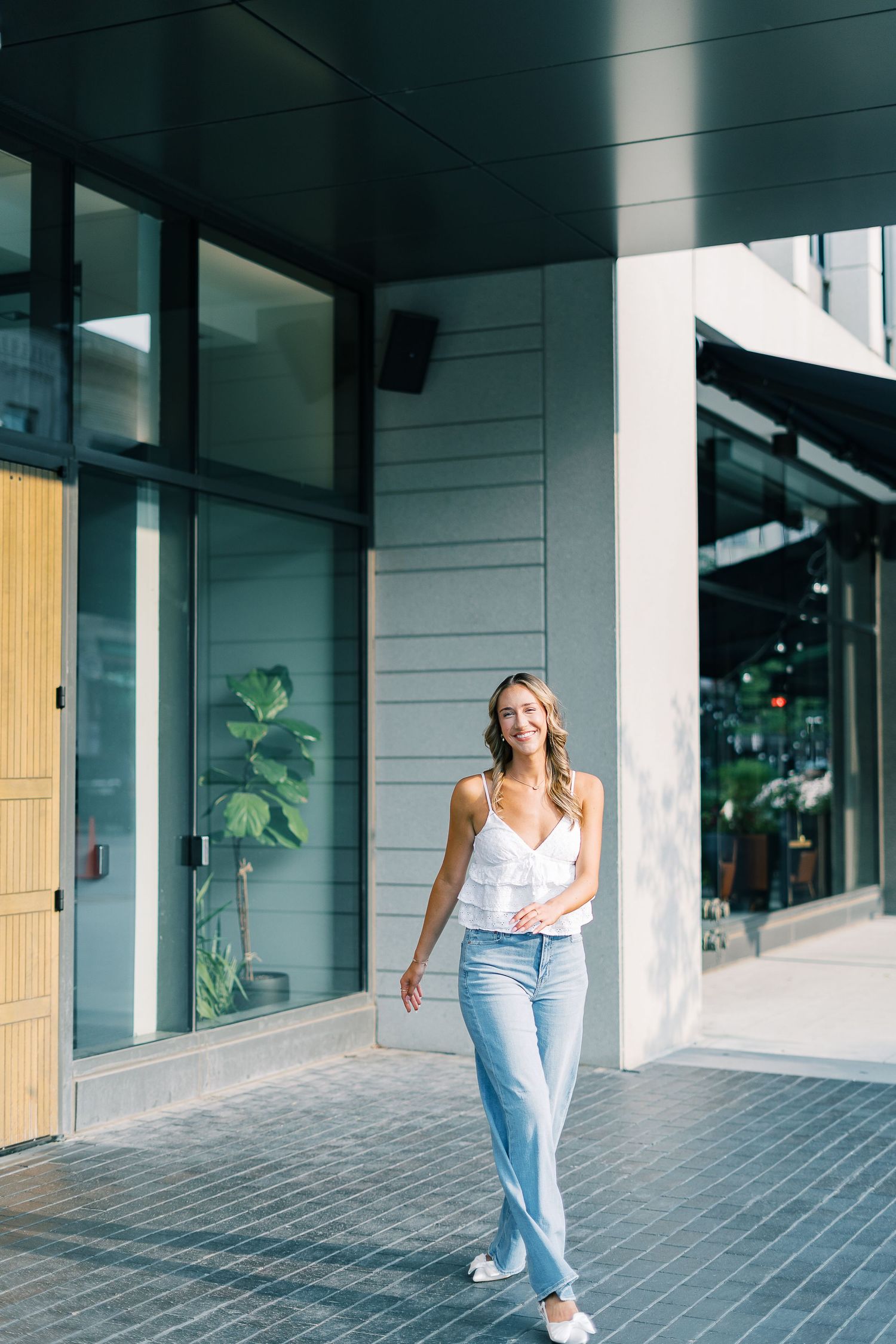 Casual street fashion sequence showing movement in jeans and white top against modern urban architecture.