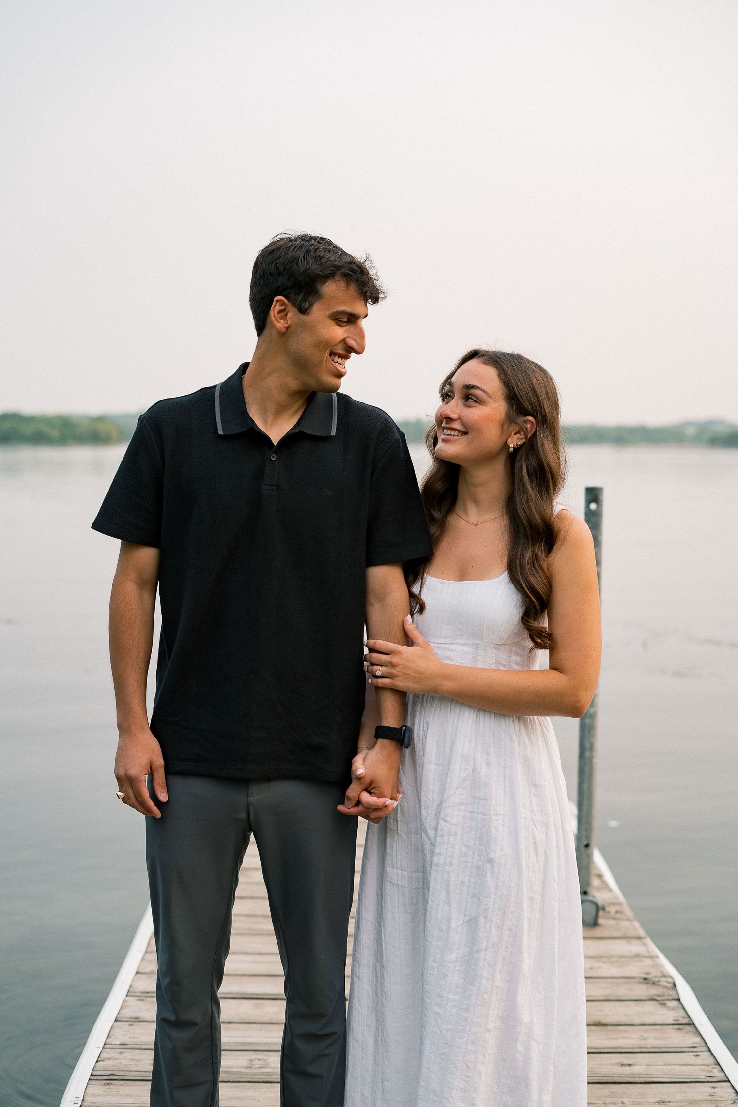 A happy couple shares a joyful moment together on a lakeside dock.
