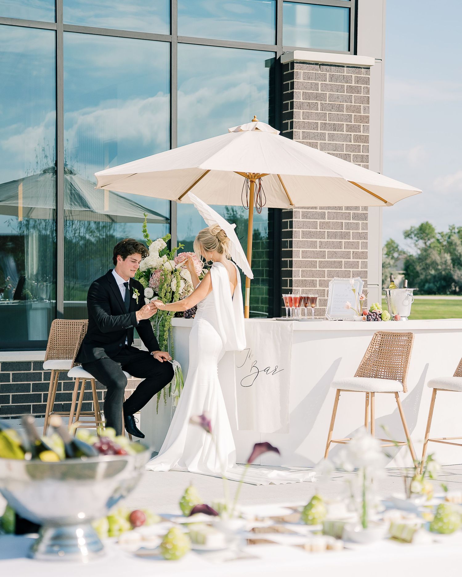 A couple shares a romantic moment on an outdoor terrace with white umbrellas and elegant table settings.
