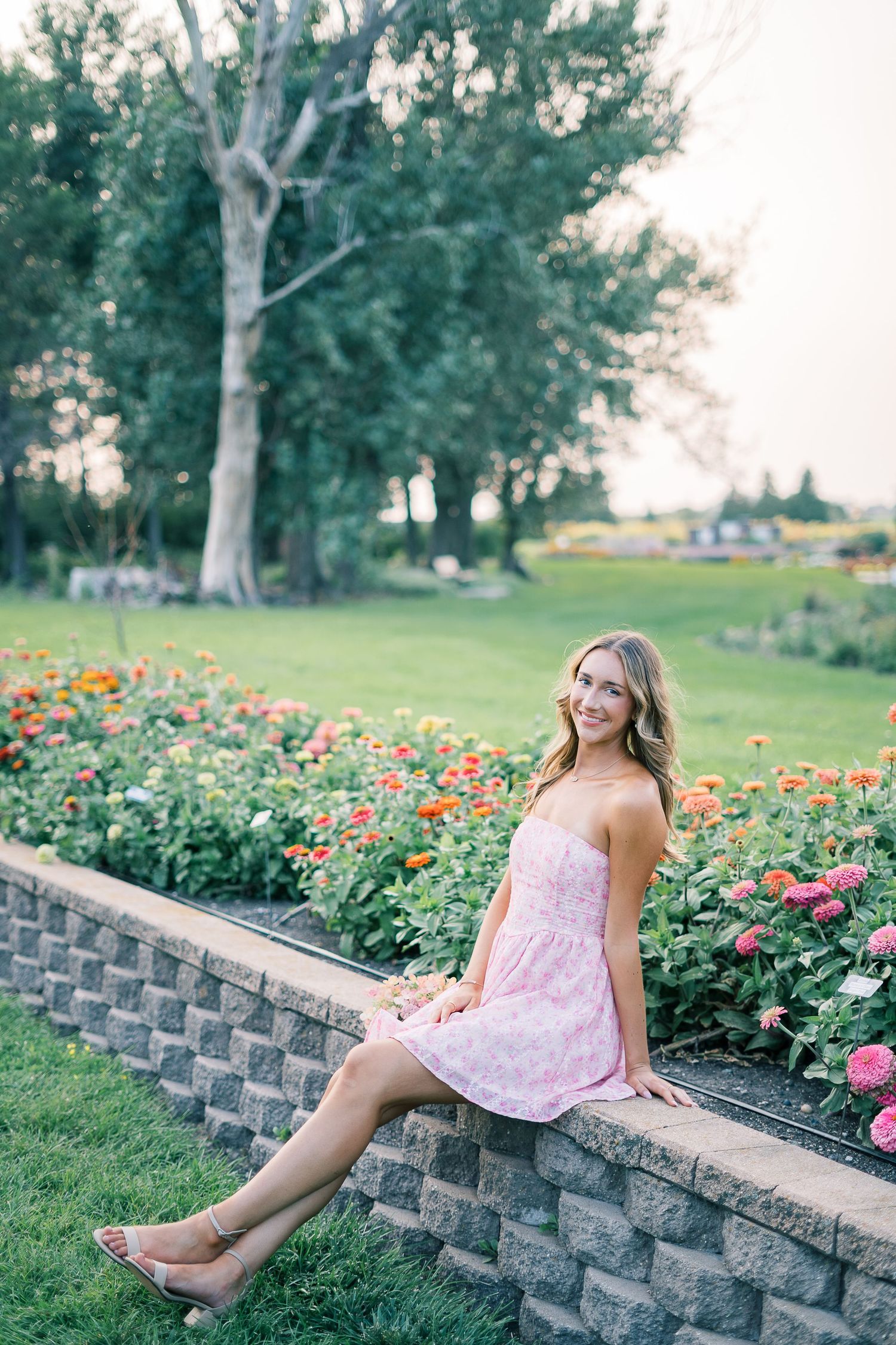 Pink sundress photoshoot by a floral garden wall during golden hour.