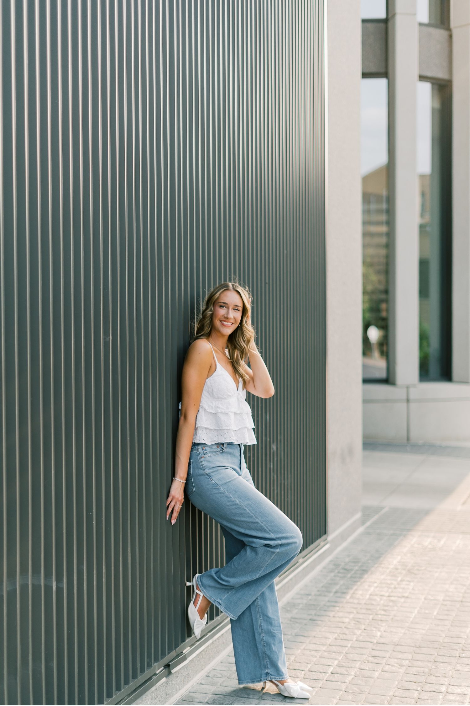 Modern architectural photo series showing a woman in white top and blue pants posing against striped wall panels.