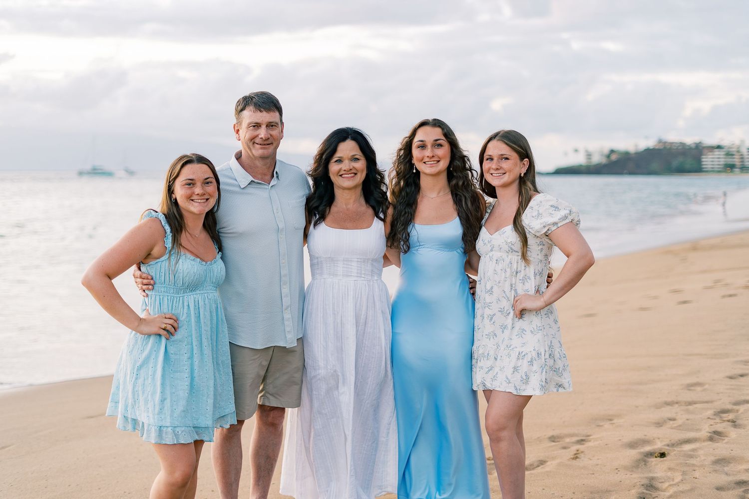 Group photo on a Hawaiian beach with ocean and palm trees in the background.