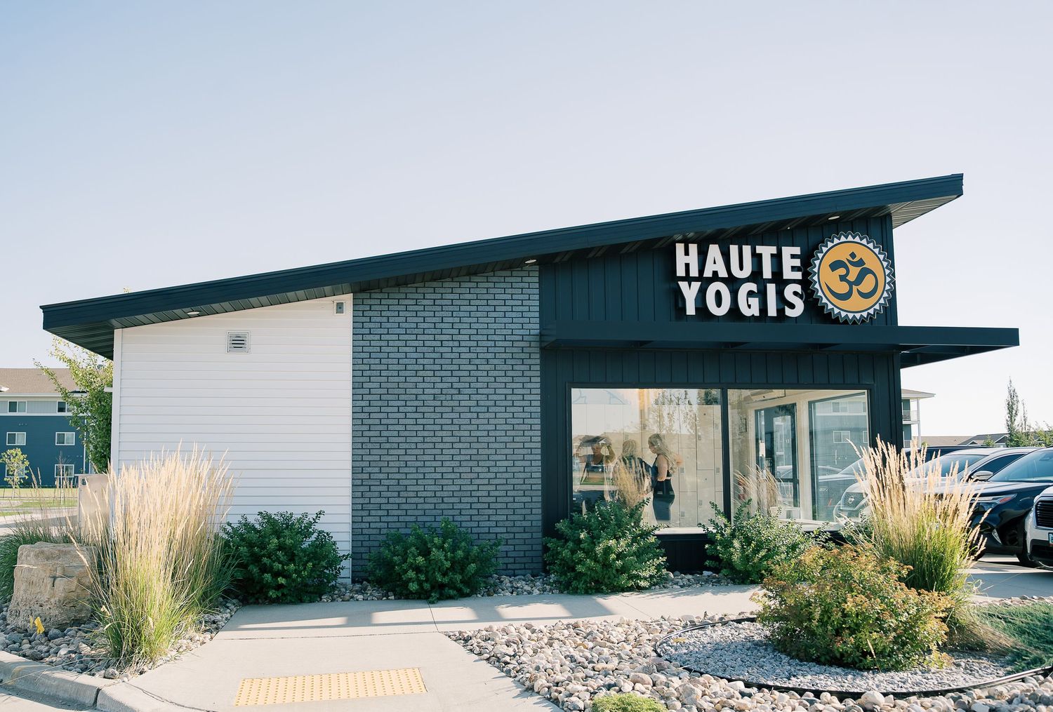 Modern black and white commercial building exterior with ornamental grasses and minimalist design elements.