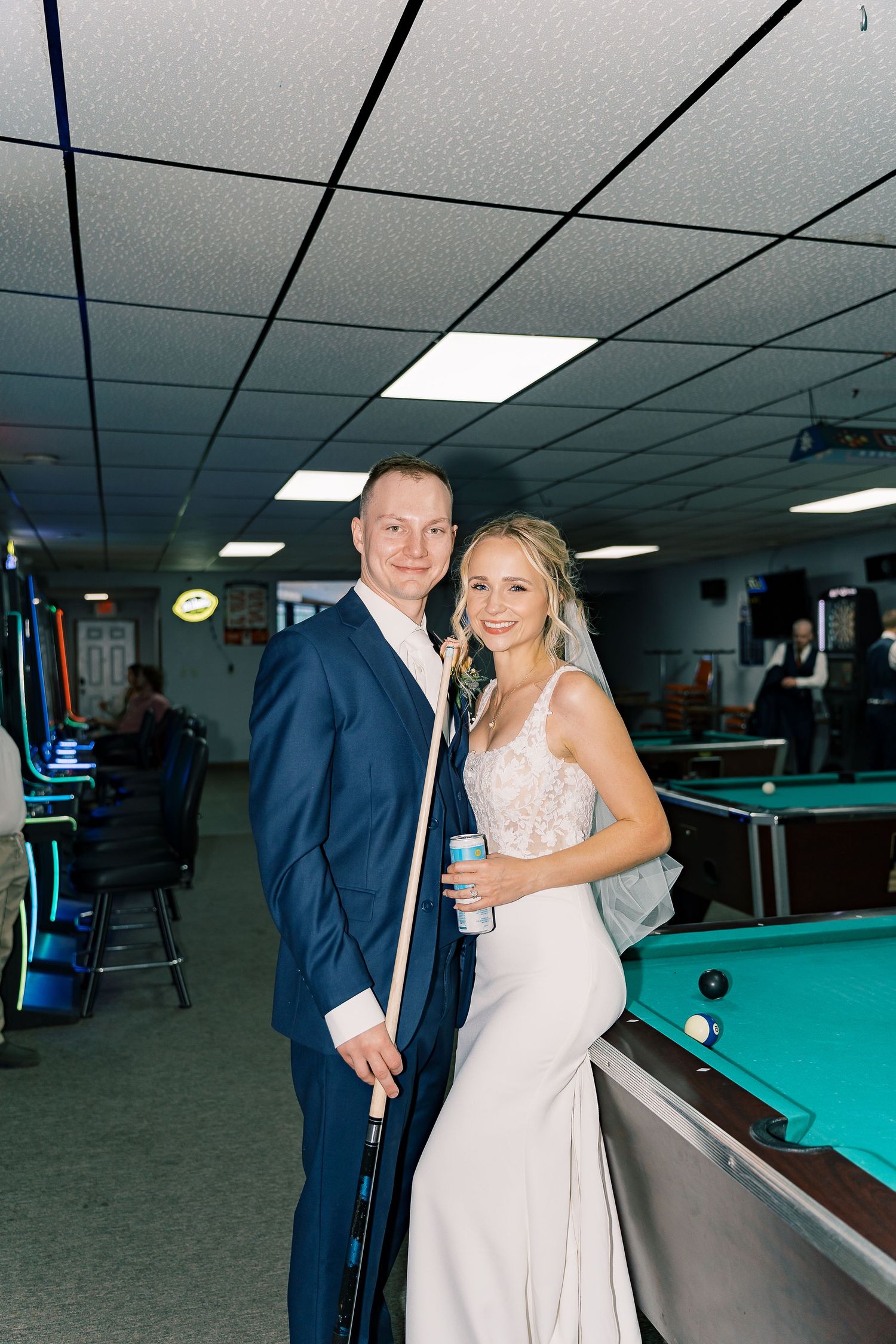 A couple in formal attire shares a romantic moment while playing pool in a billiards room.