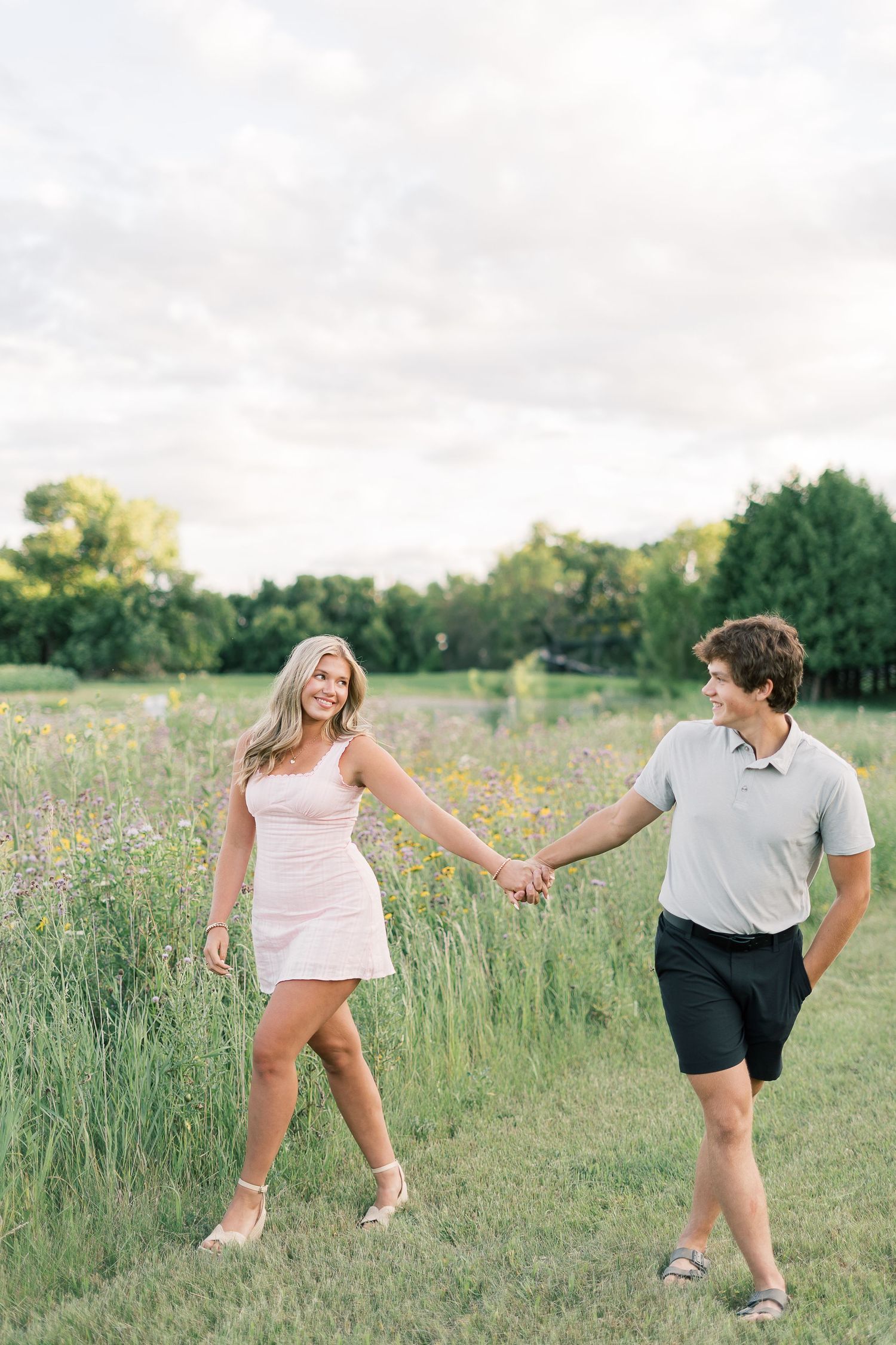 Couple playfully poses together in sunny meadow with wildflowers in a series of candid shots.