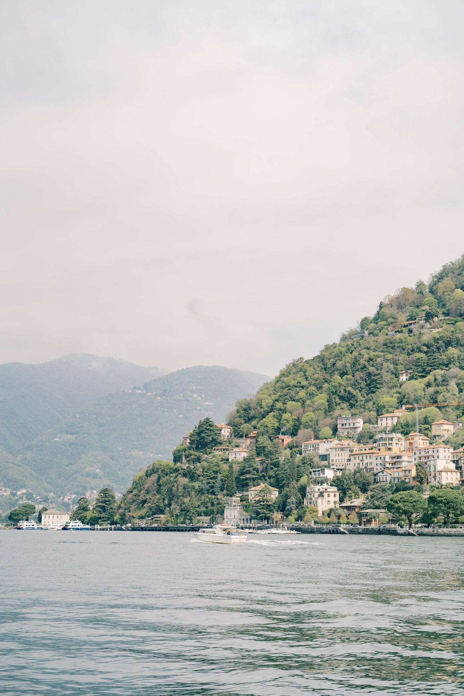 Coastal Mediterranean village with houses nestled on hillside overlooking calm blue waters.