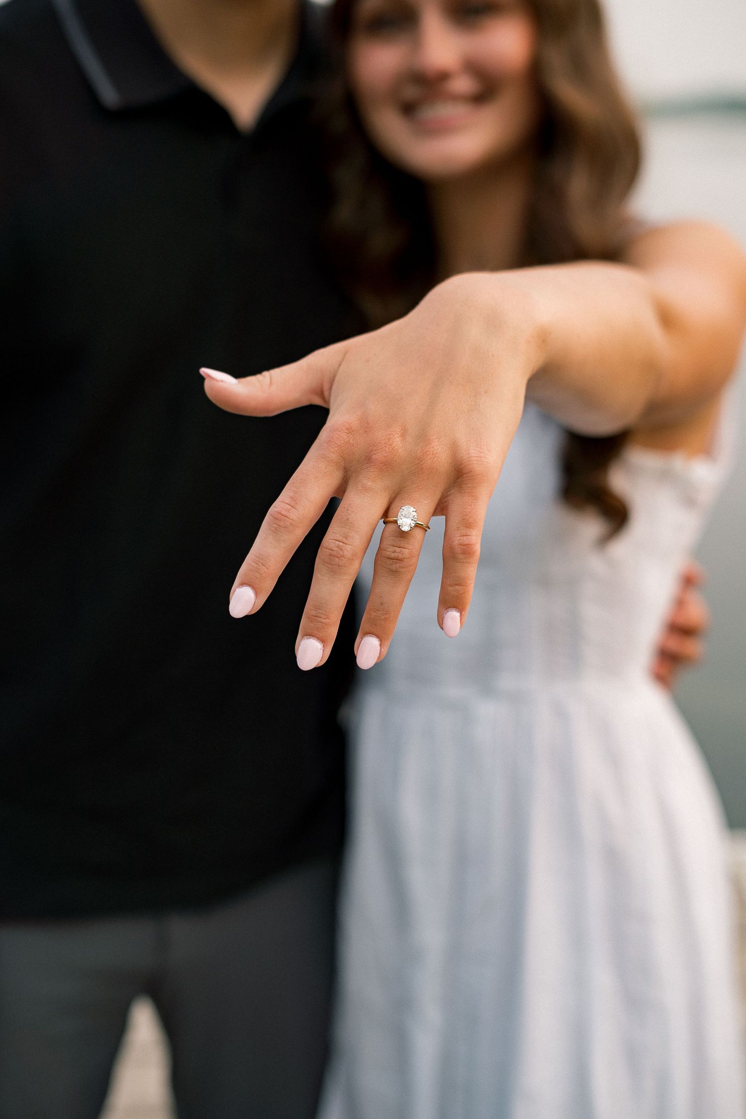 Close-up shots of a woman's hand showing off an engagement ring while wearing a light blue dress.
