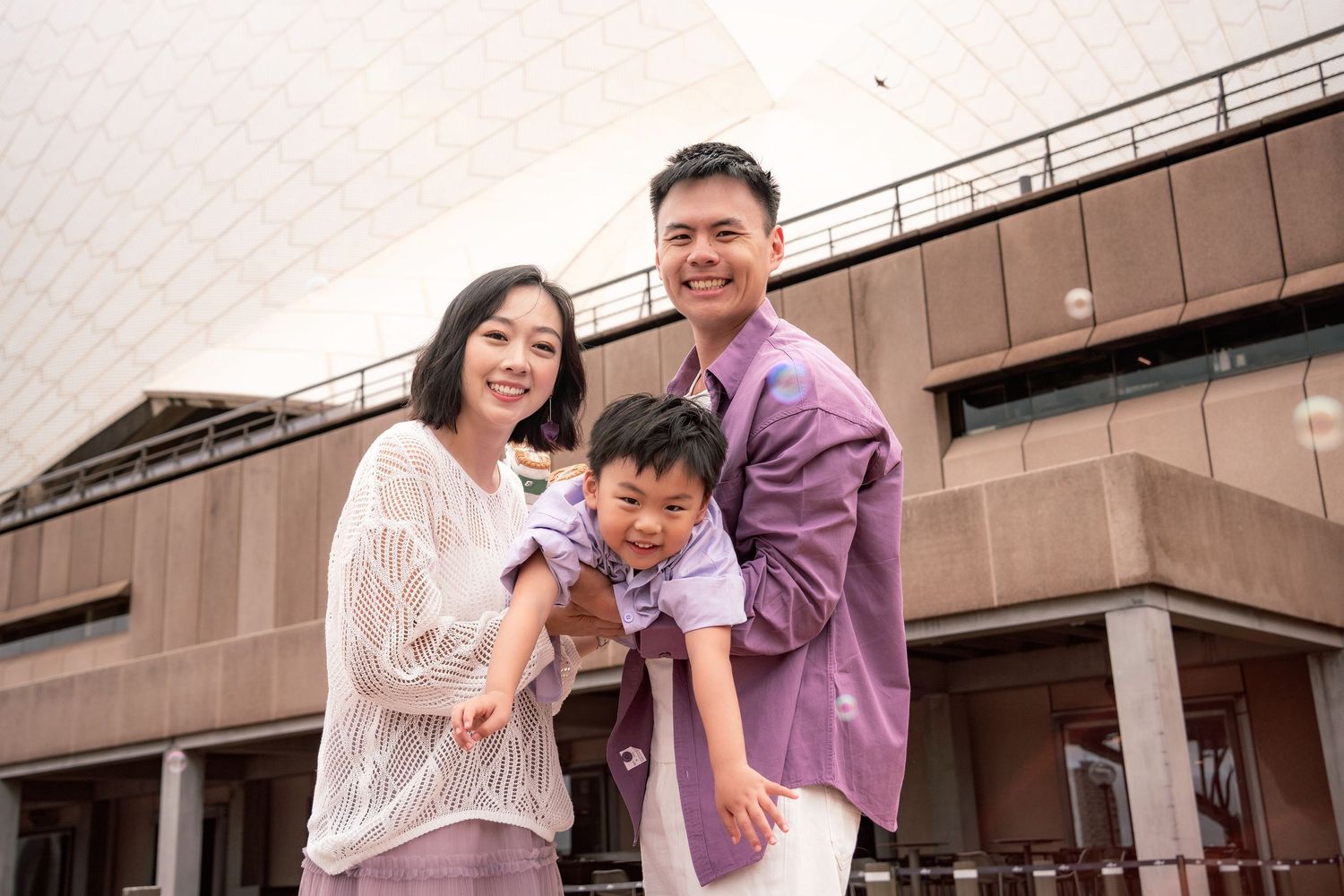 Couple sharing joyful moments together in a casual outdoor setting with brown building exterior in the background.