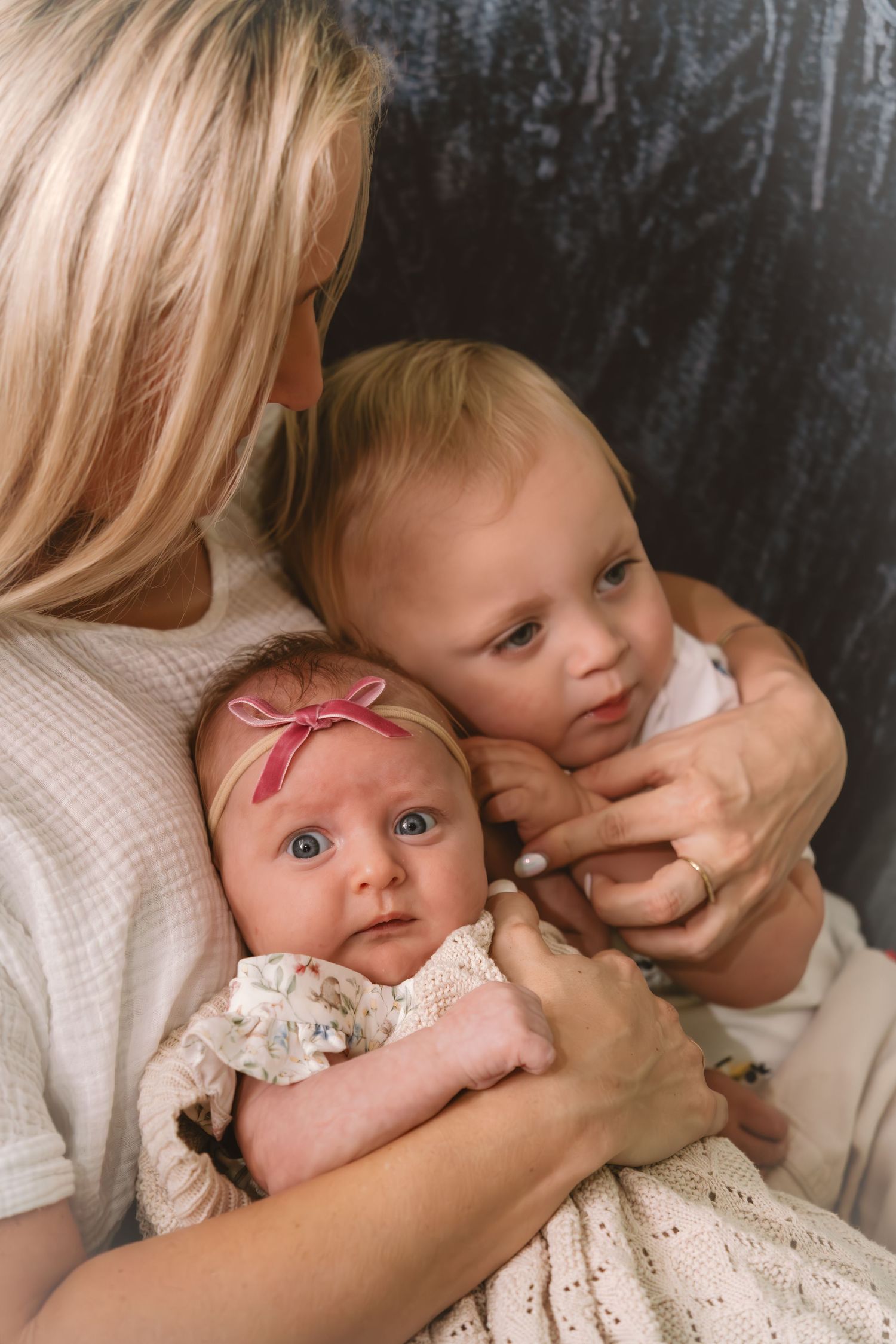 A series of close-up photos showing a baby in a white lace dress being held and comforted by gentle hands.