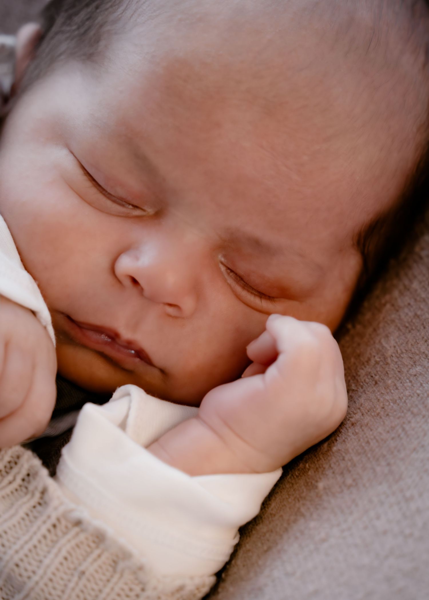 A sleeping infant rests peacefully on a white knit blanket in a series of close-up shots.