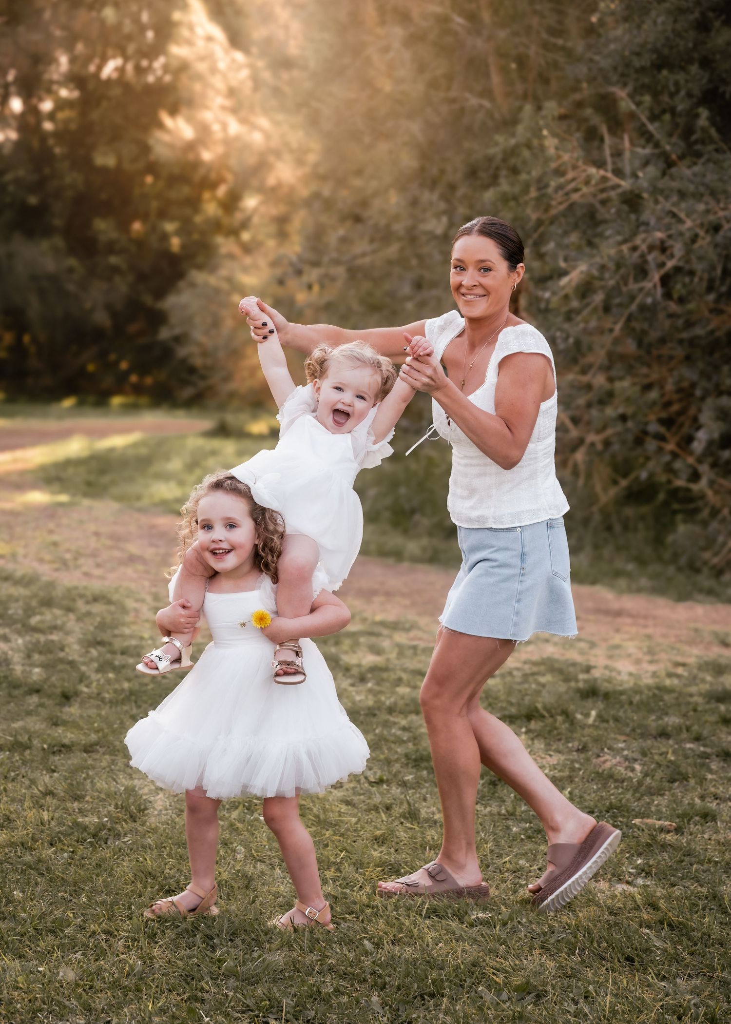 A heartwarming sequence of playful moments between parent and child dancing together in white dresses on a grassy field.