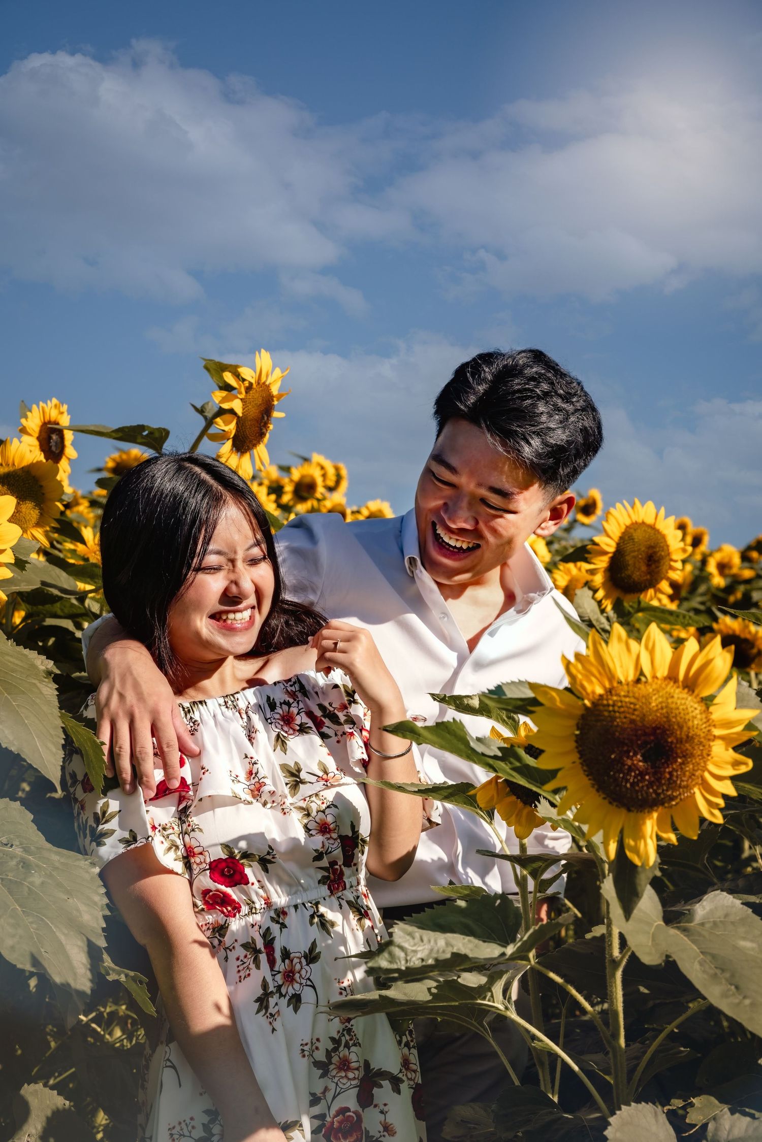 Joyful couple enjoys a sunny afternoon in a vibrant sunflower field, creating candid and playful moments together.