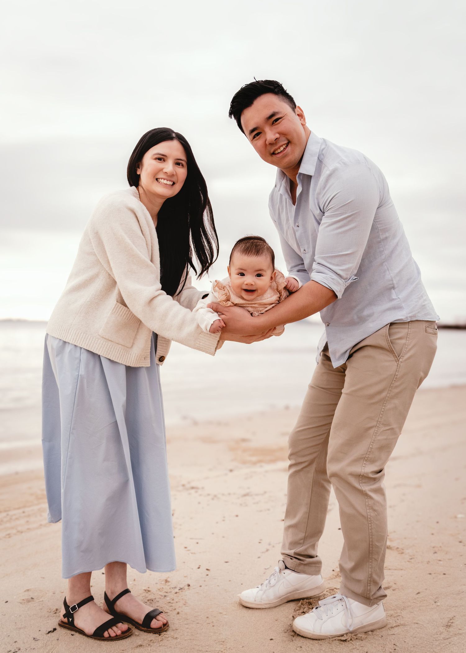 A family shares joyful moments together while walking on a sandy beach at sunset.