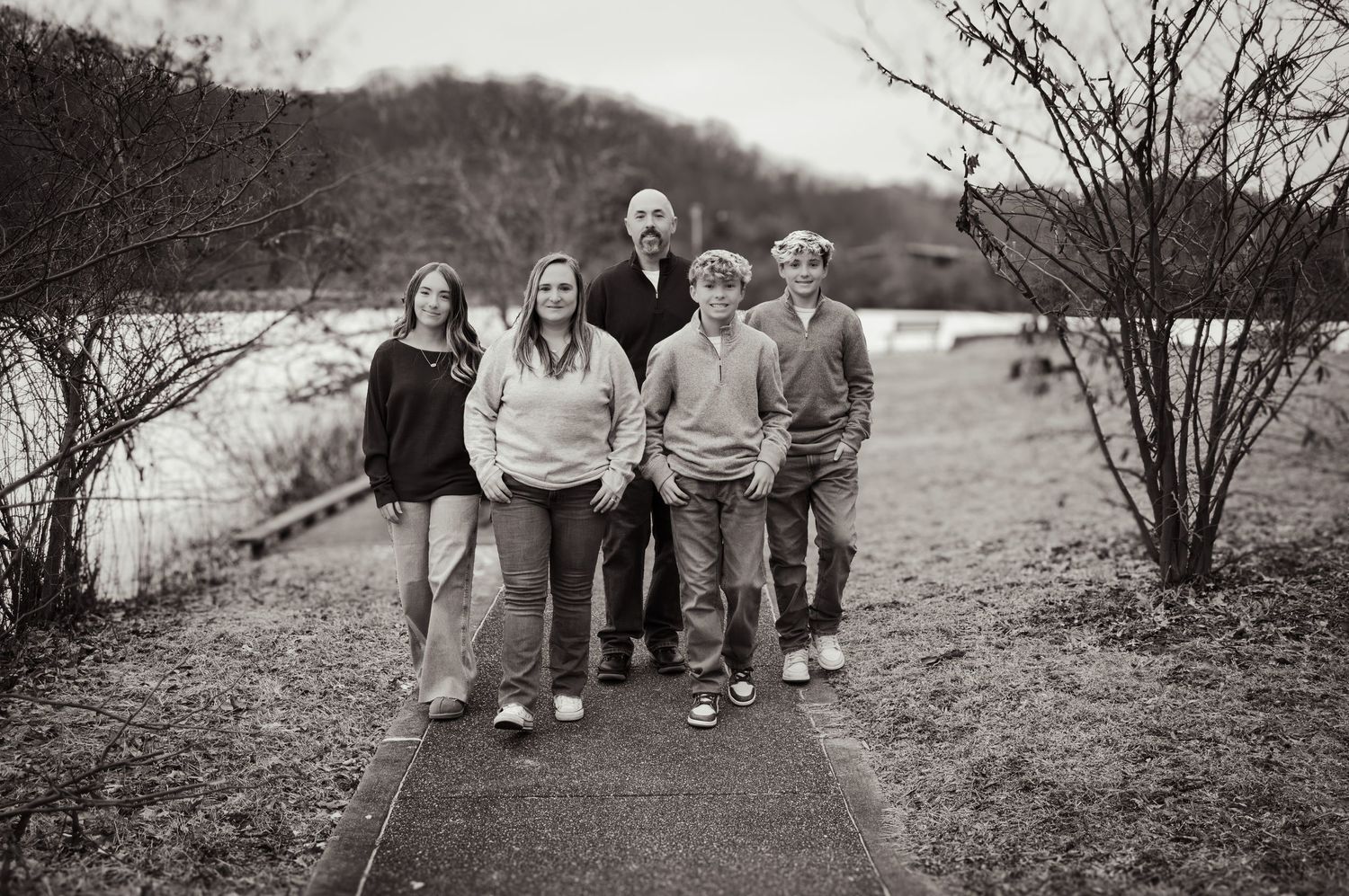 Black and white collage of candid outdoor family photos showing people walking and posing together on a path.