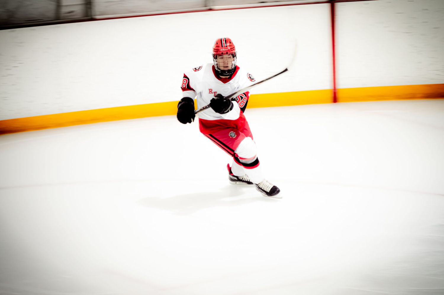Hockey players in red uniforms practicing stick handling on ice.
