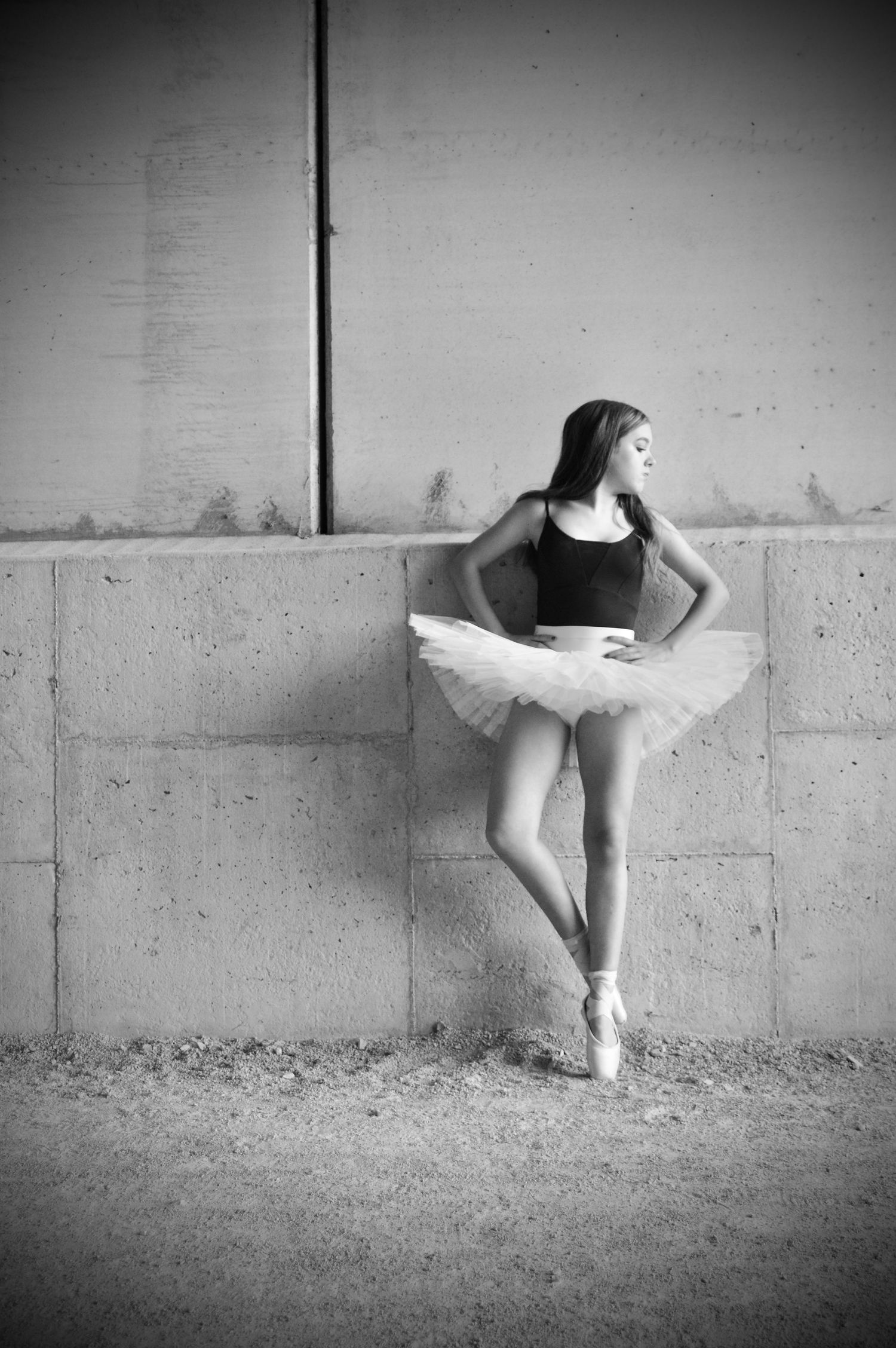 Black and white artistic dance photography against textured concrete wall.