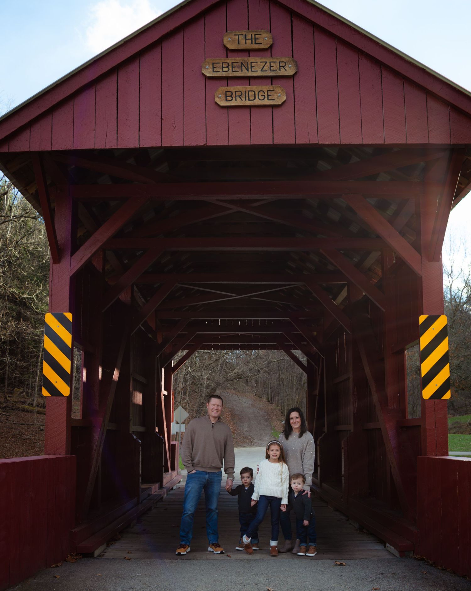 A sequence of photos showing people standing inside a rustic red covered bridge during a photo session.