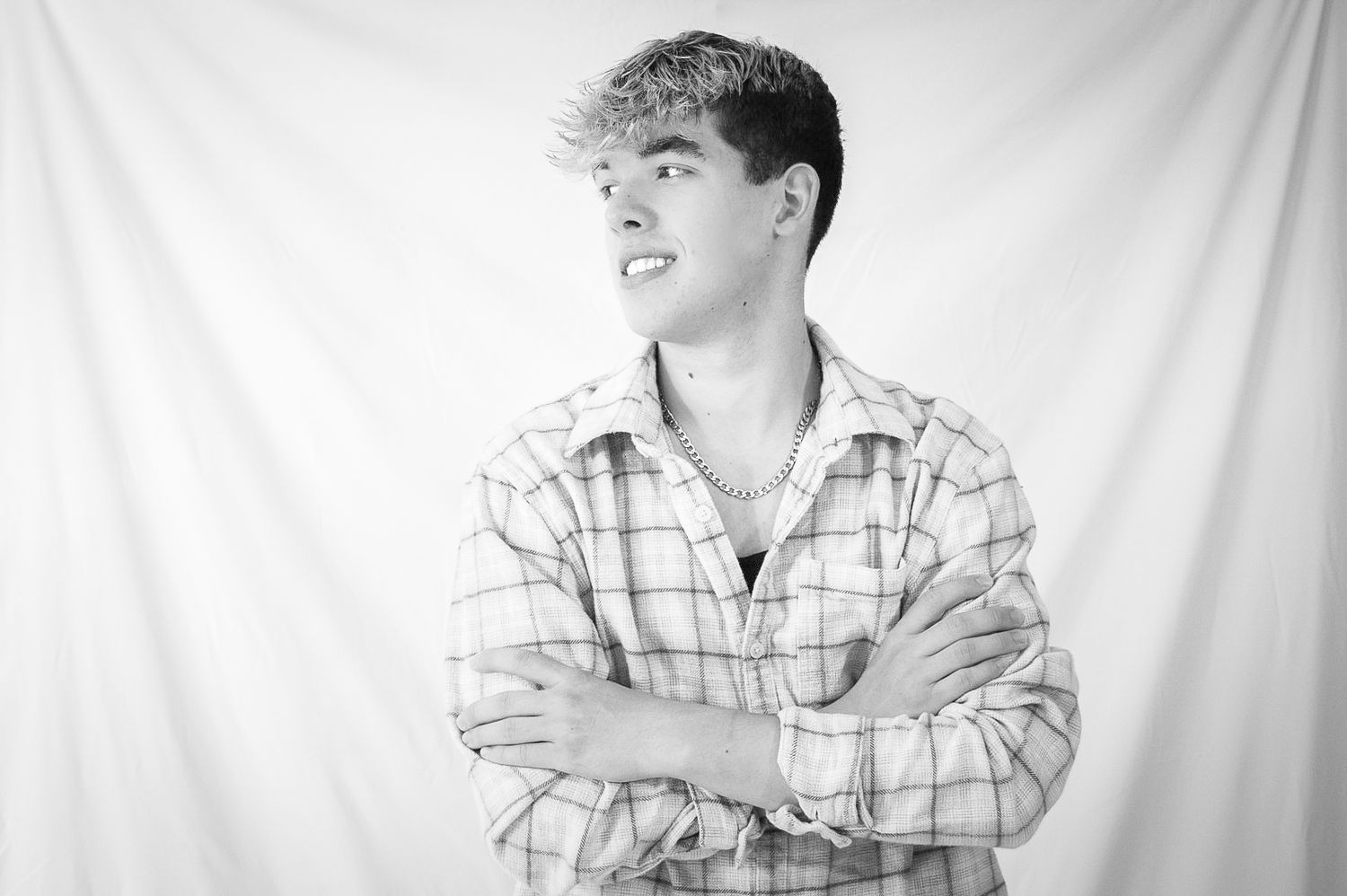 Black and white portrait of someone in a plaid shirt against a white backdrop.