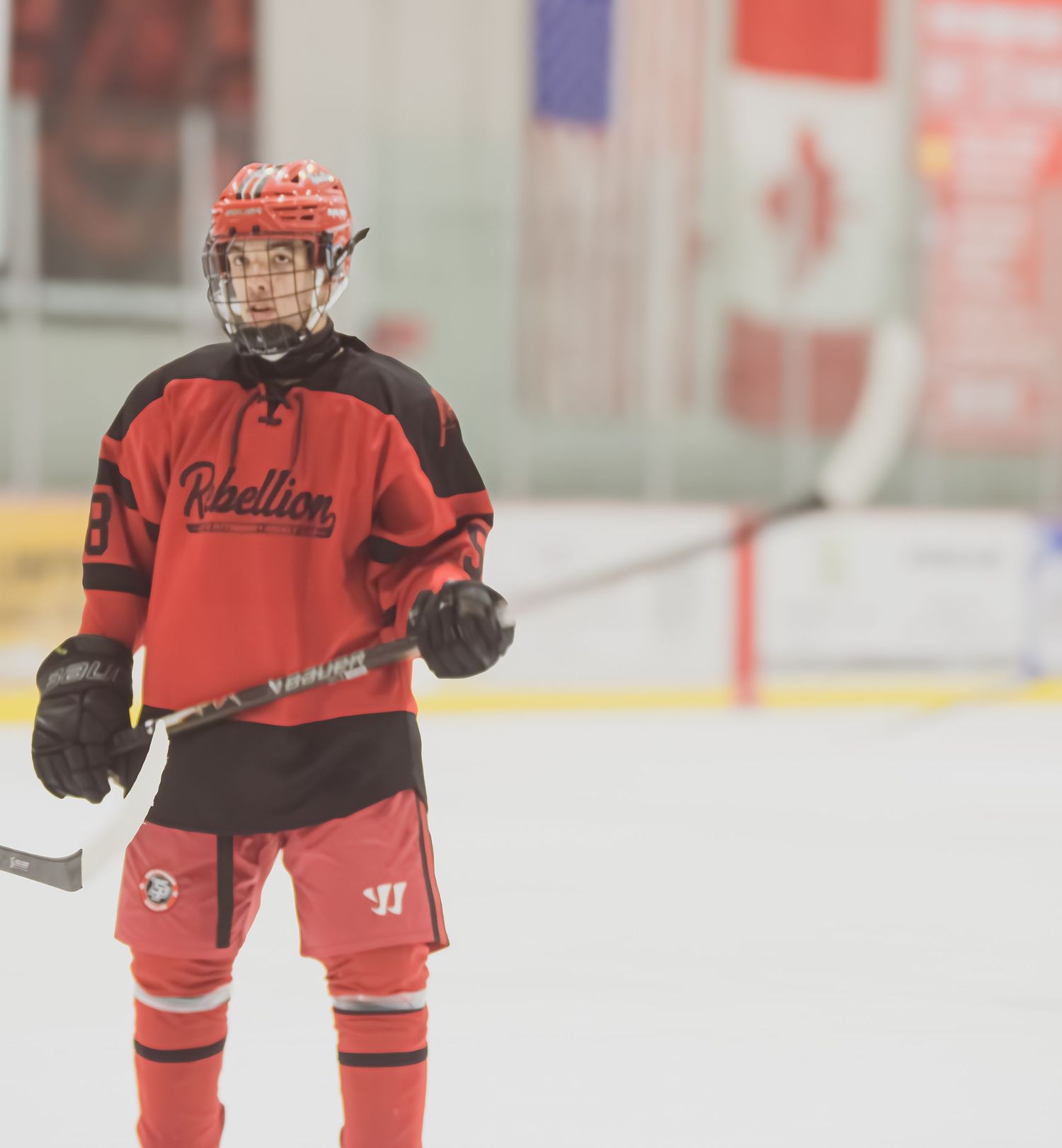 Hockey players in red uniforms practicing on indoor ice rink.