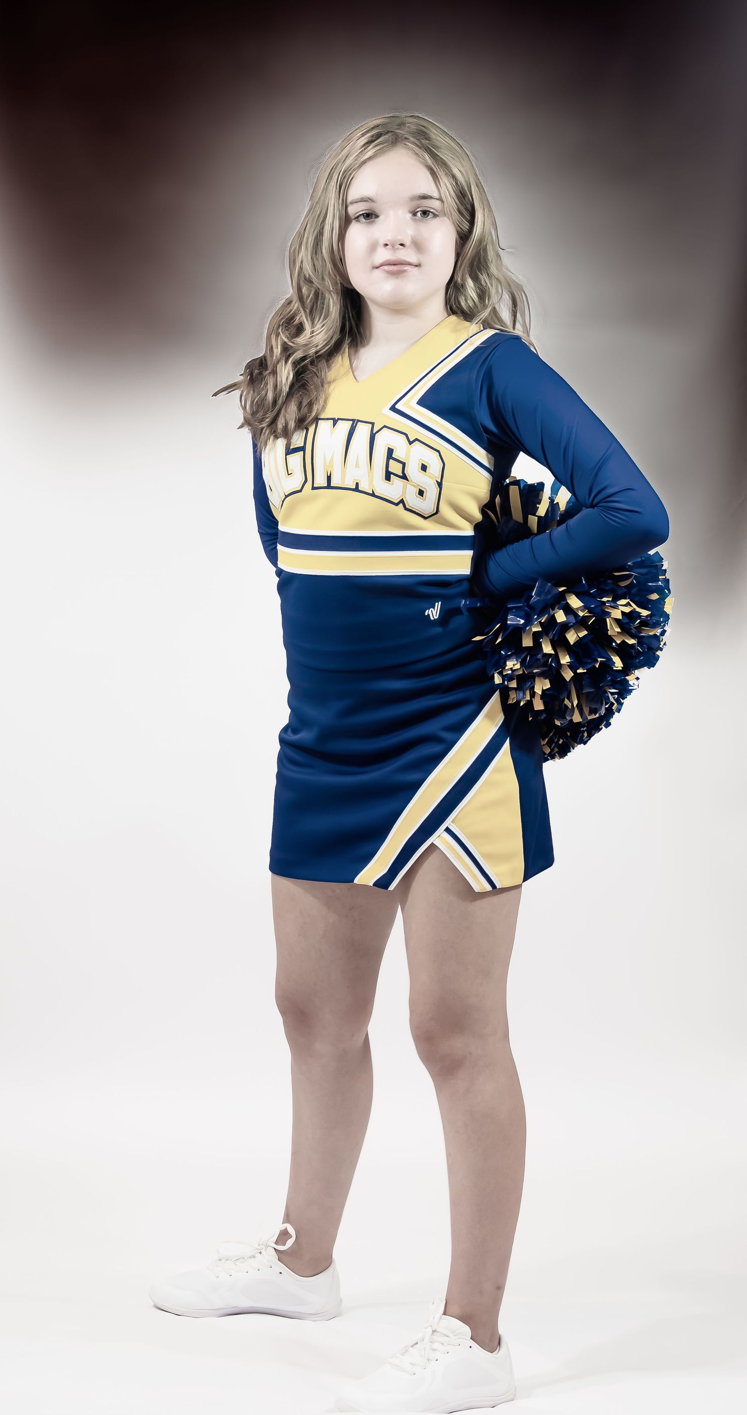 A cheerleader in a blue and yellow uniform poses with pom poms against a light background.