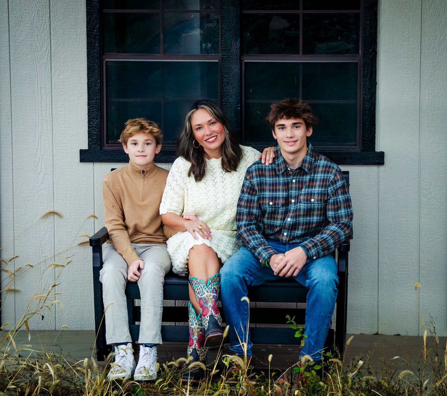 A group sits together on a porch step wearing casual clothing including plaid shirts and jeans.