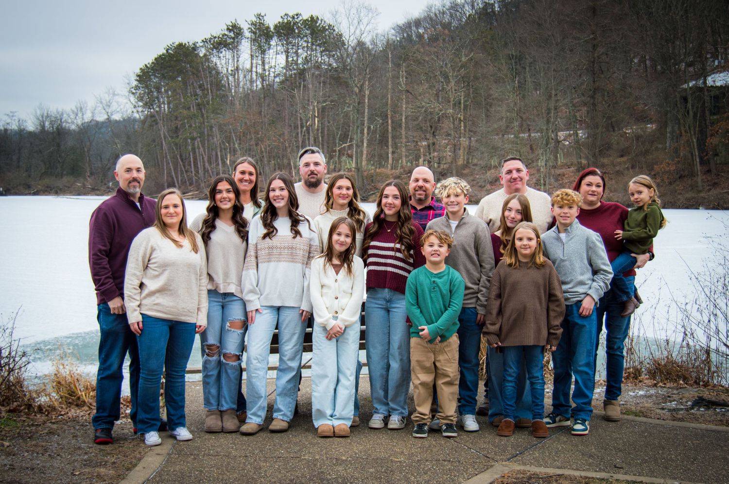 A group of people lined up outdoors against a winter lake backdrop wearing casual clothing.