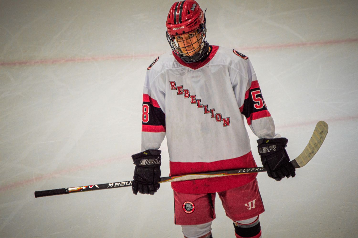 Hockey players in red jerseys and helmets skating on ice during a game.
