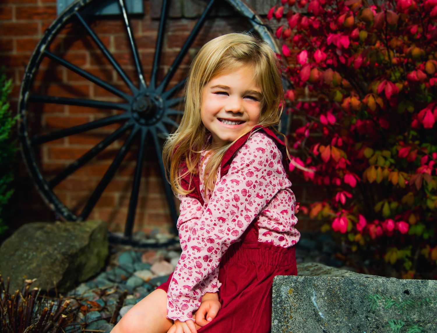A series of outdoor autumn portraits featuring a pink floral dress against vibrant red fall foliage and brick wall backdrop.