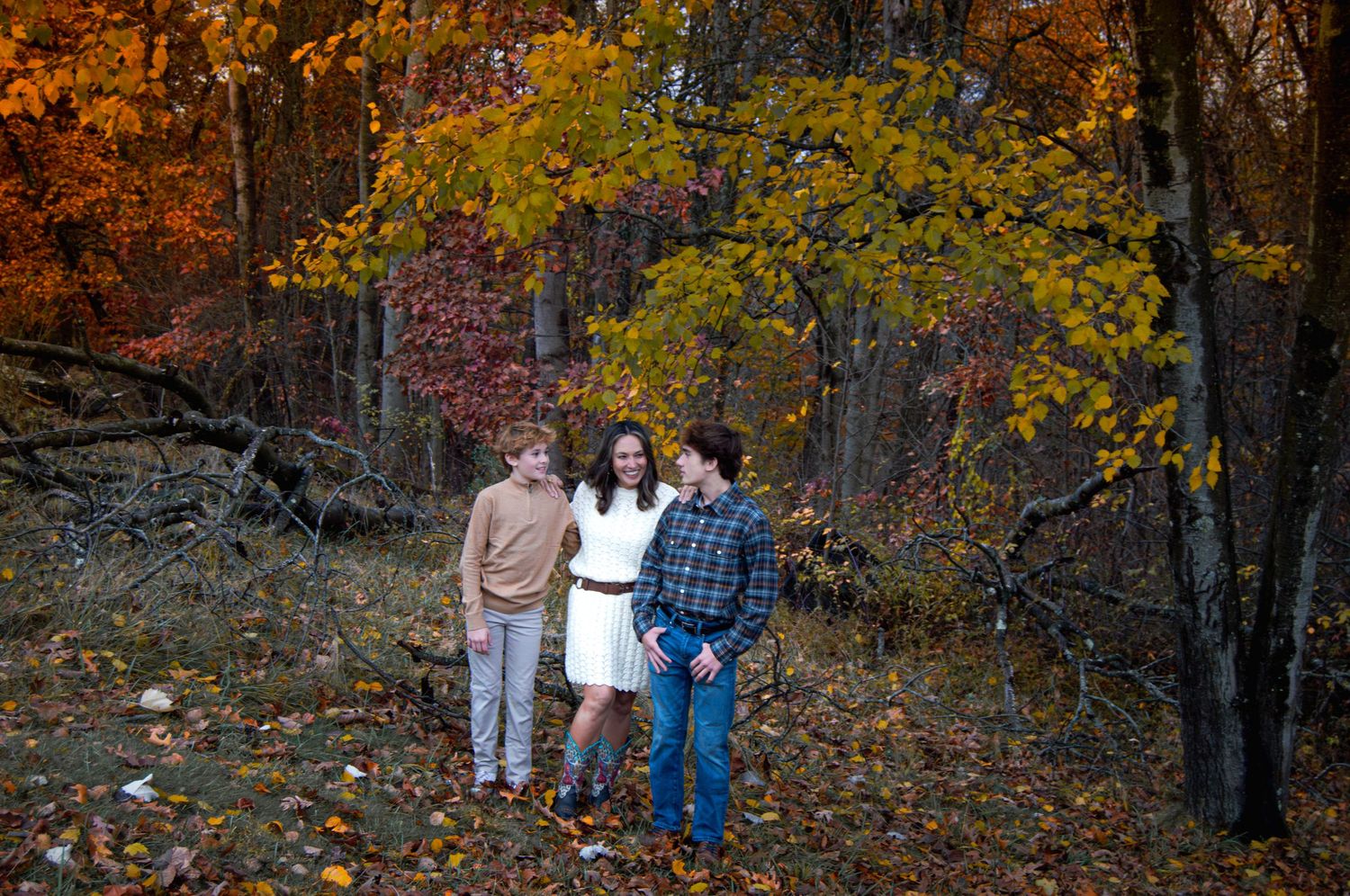 Group enjoying a casual outdoor photoshoot in a wooded area with golden autumn leaves.