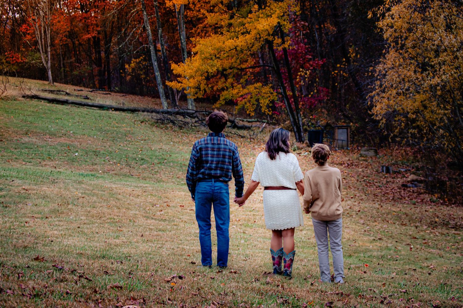 Family walking together through a scenic autumn landscape with colorful fall foliage.