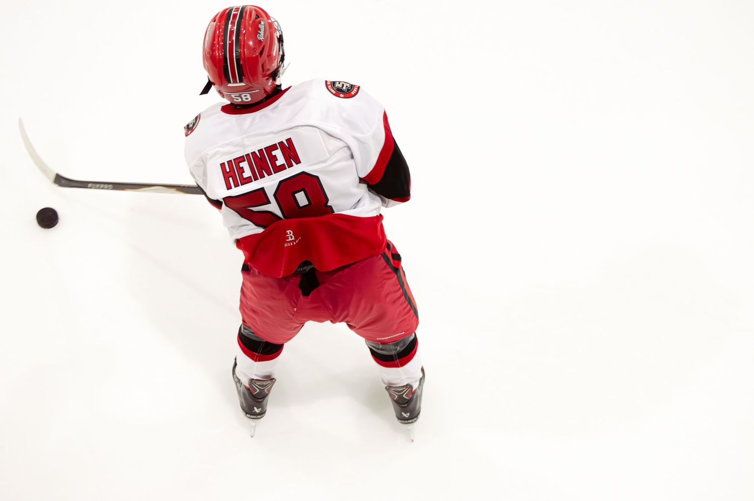 Hockey player in red and white uniform skating on ice during practice session.