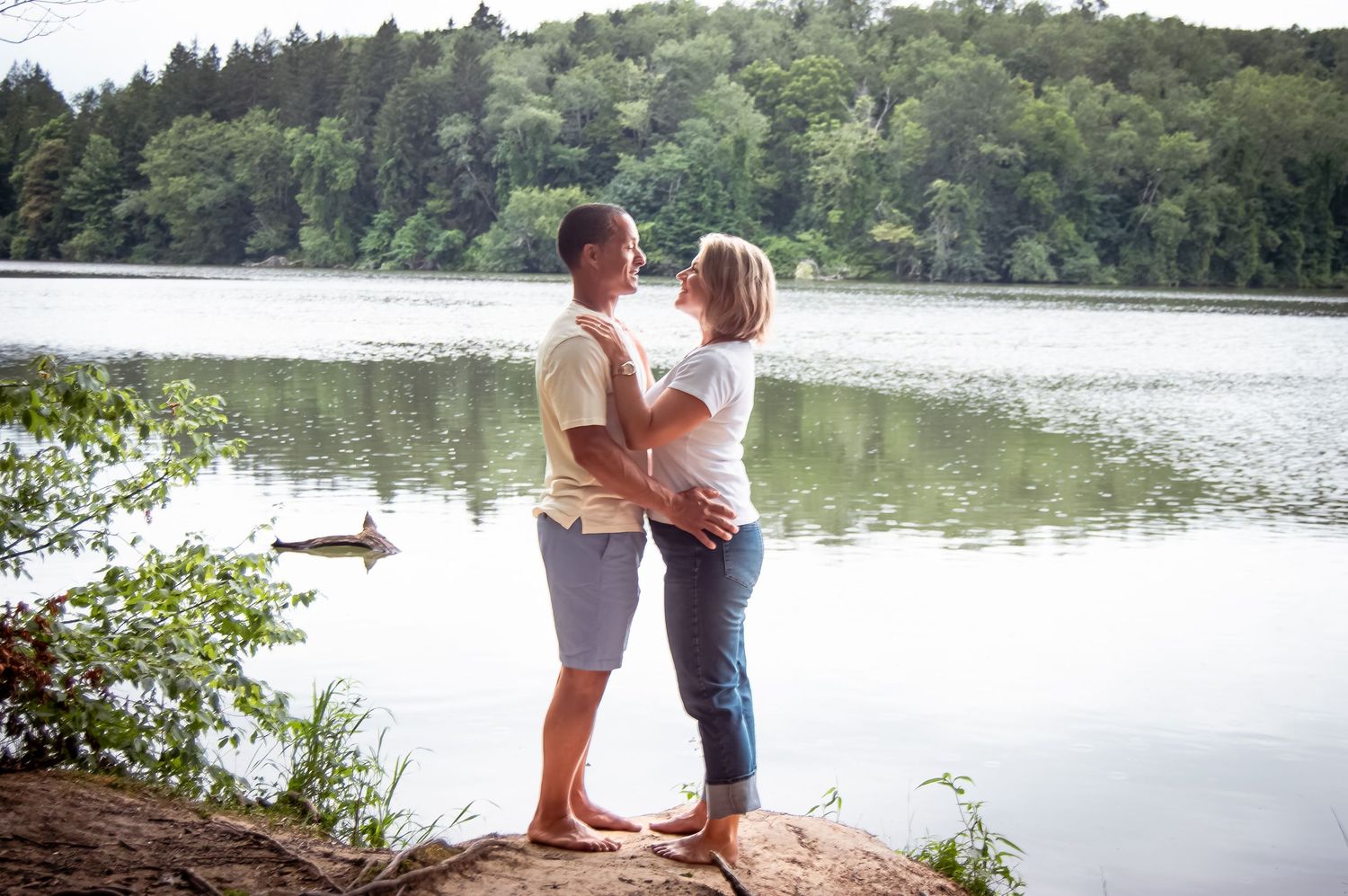 Group portrait captured at a lakeside beach with trees and calm waters in the background.