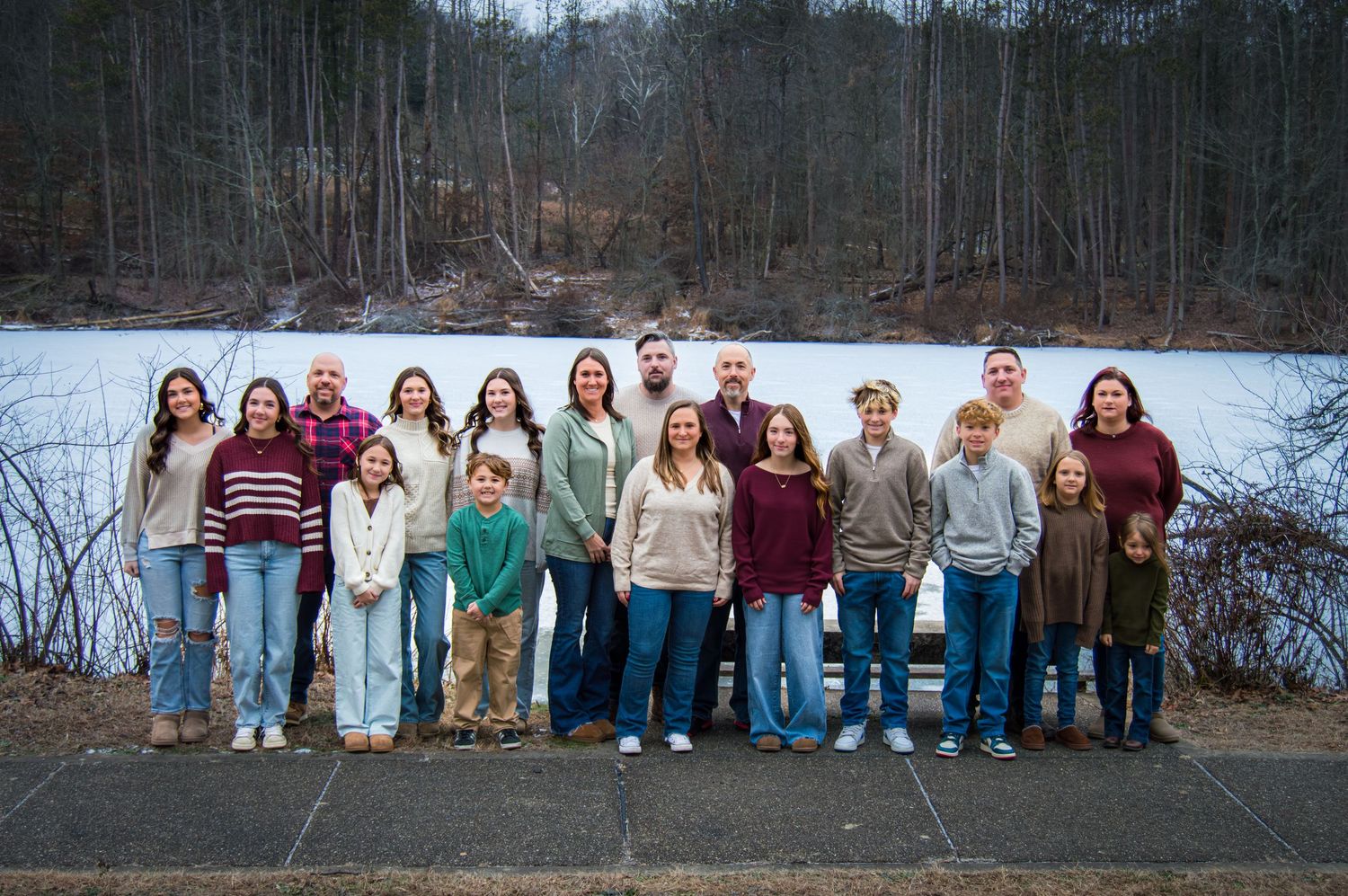 Group of people standing together outdoors against a winter landscape with trees and snow in the background.