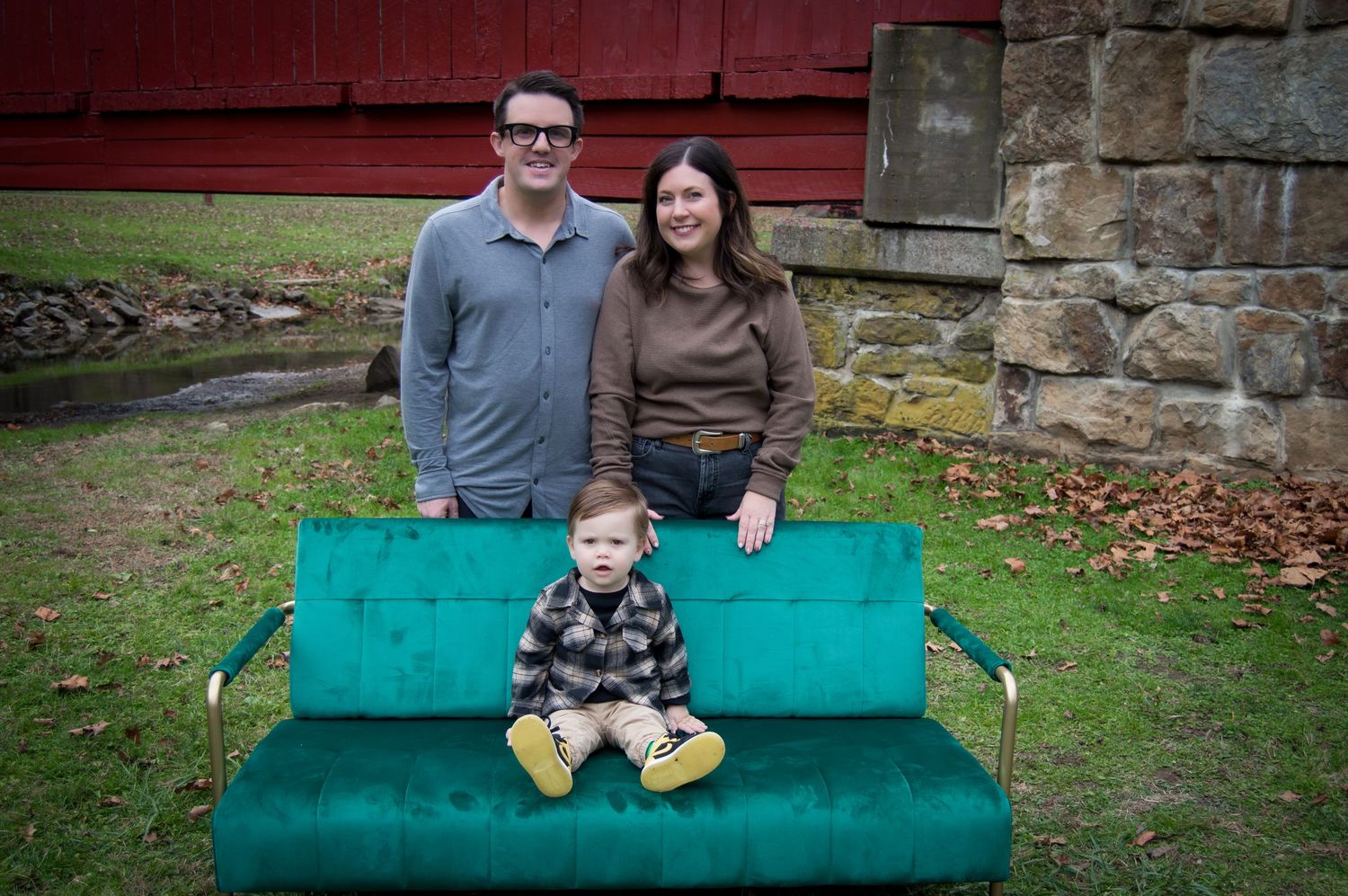 Family sitting together on a bright turquoise outdoor bench against a stone wall backdrop.