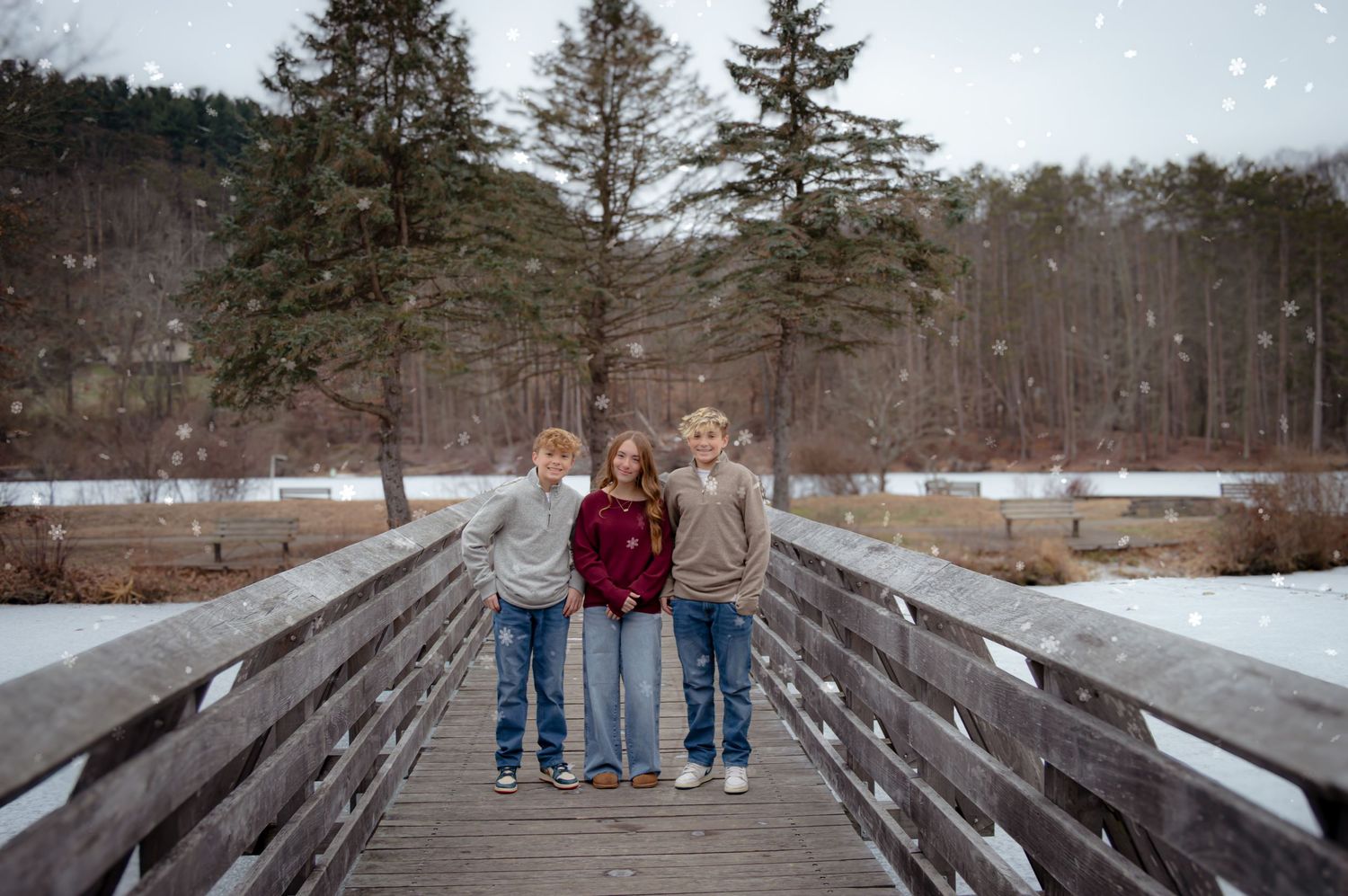 A group walking together on a snow-covered bridge in a winter forest setting.