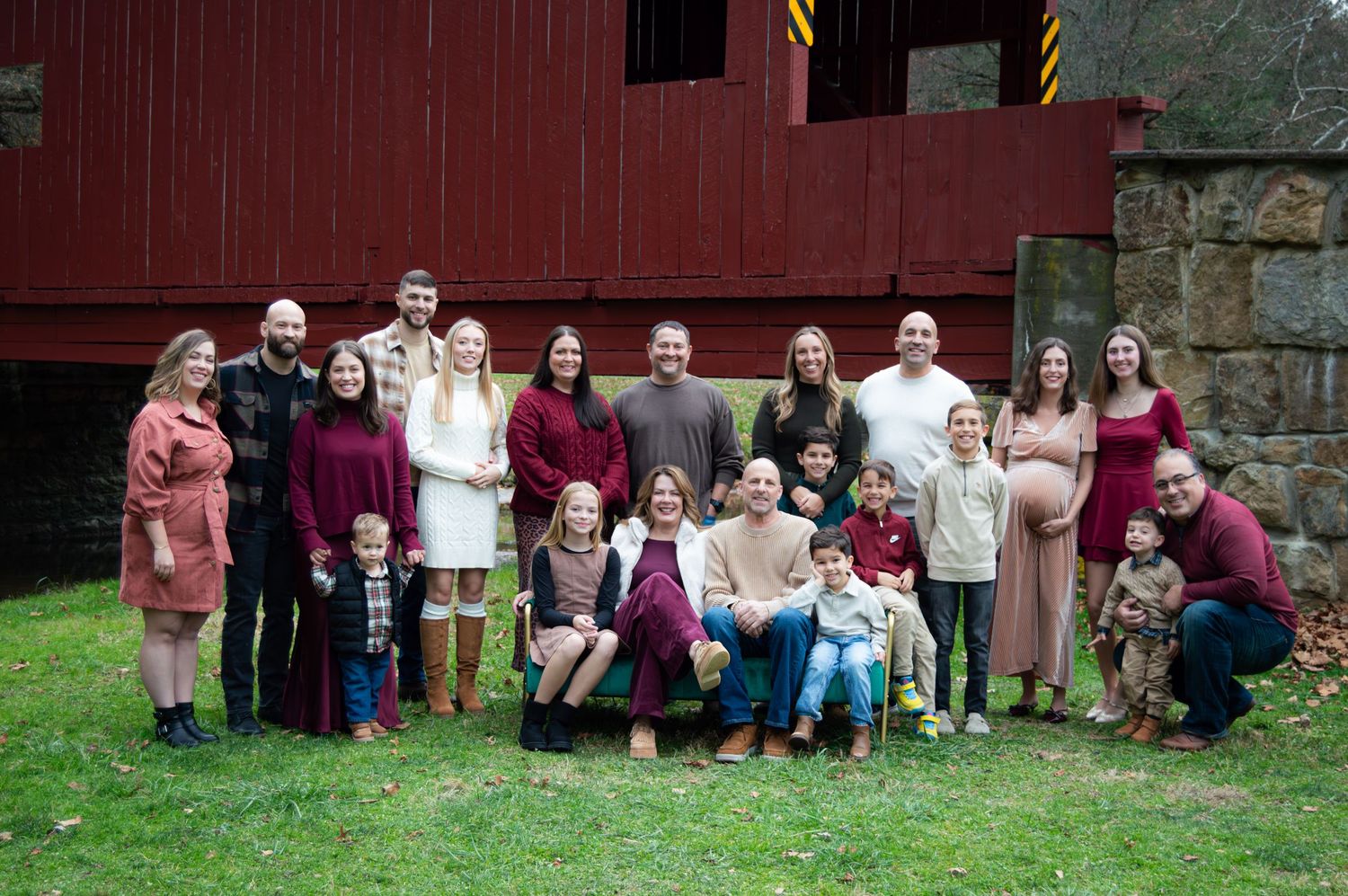 A group of people sit lined up against a stone wall outdoors for a creative photo composition.