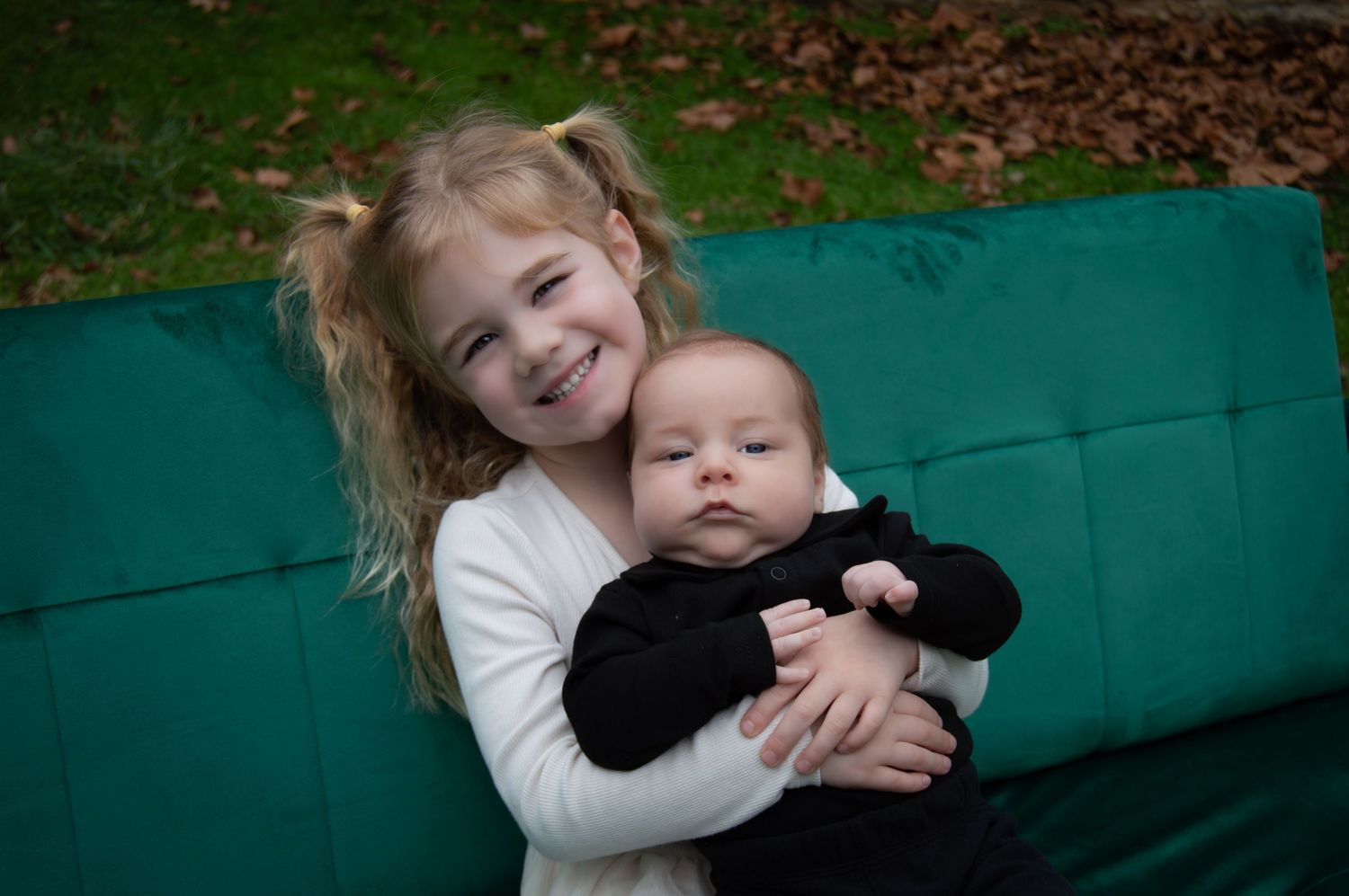 Two children share a sweet embrace while sitting outdoors on a bright turquoise bench.