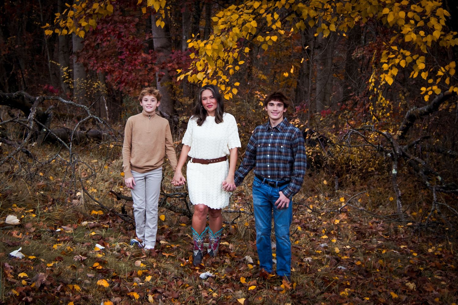 A group walks together through a wooded area with vibrant fall foliage in the background.