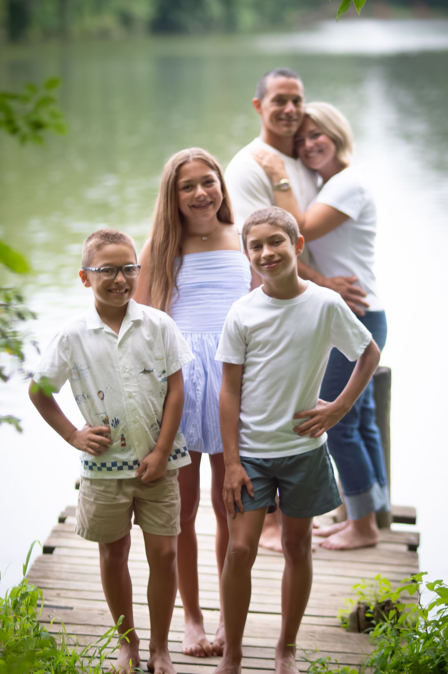 Happy family gathering on wooden dock by peaceful lake.