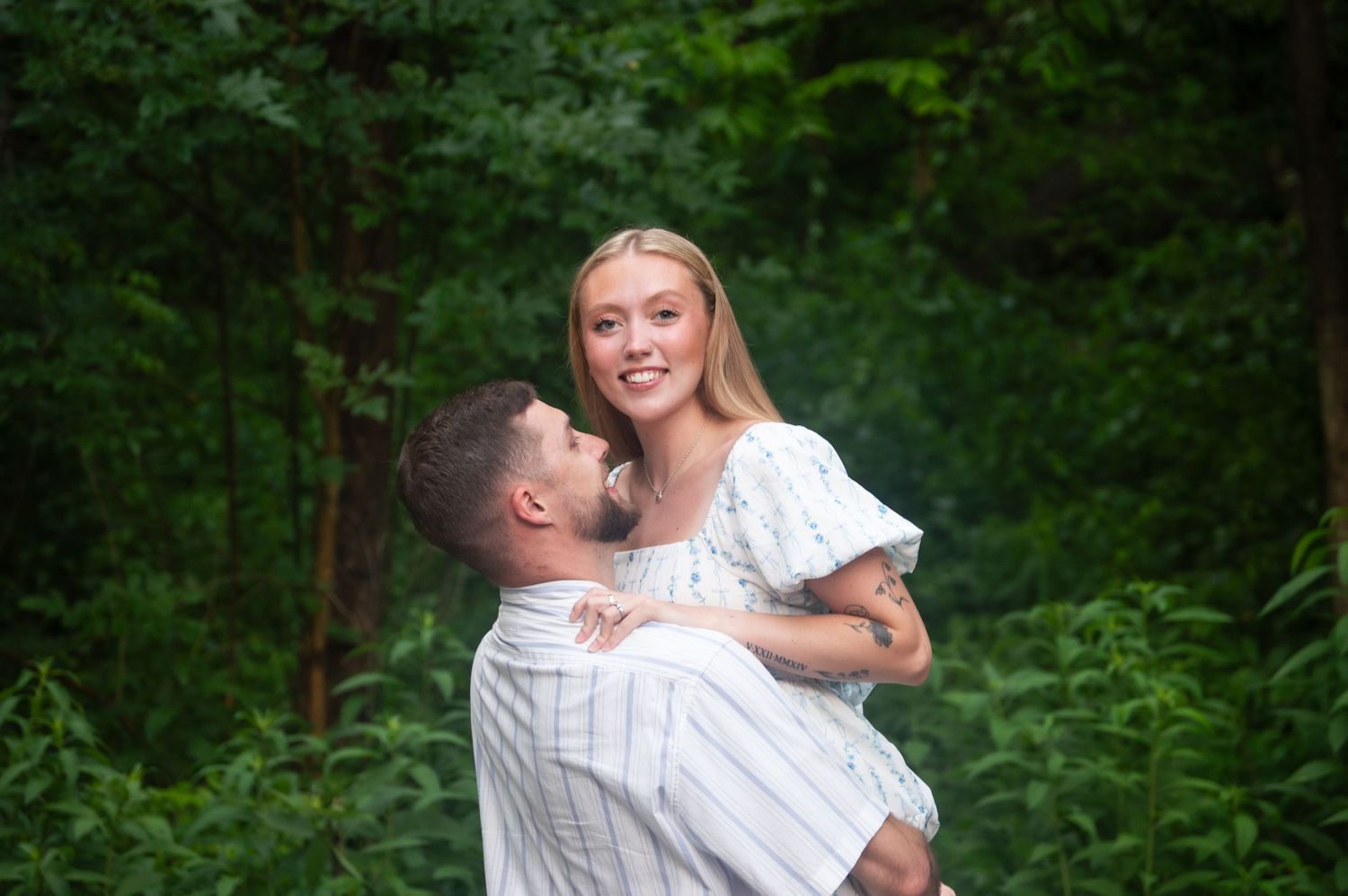 Romantic moment captured in a garden setting with stone wall backdrop.
