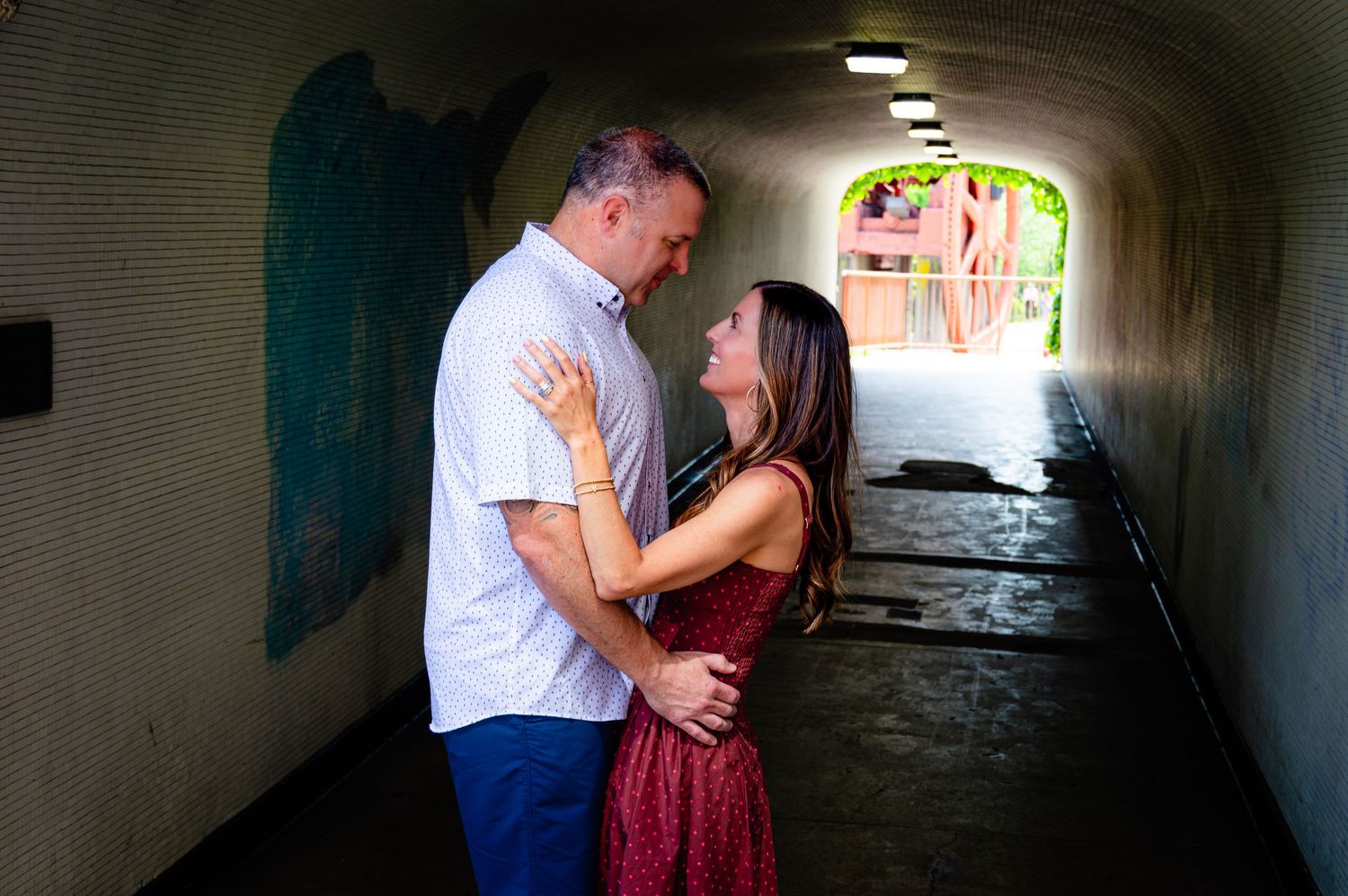Couple embracing and gazing at each other inside a colorful tunnel passageway.