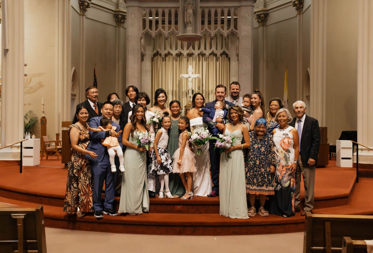 Large wedding family group photo inside a beautiful church with ornate wooden architecture.
