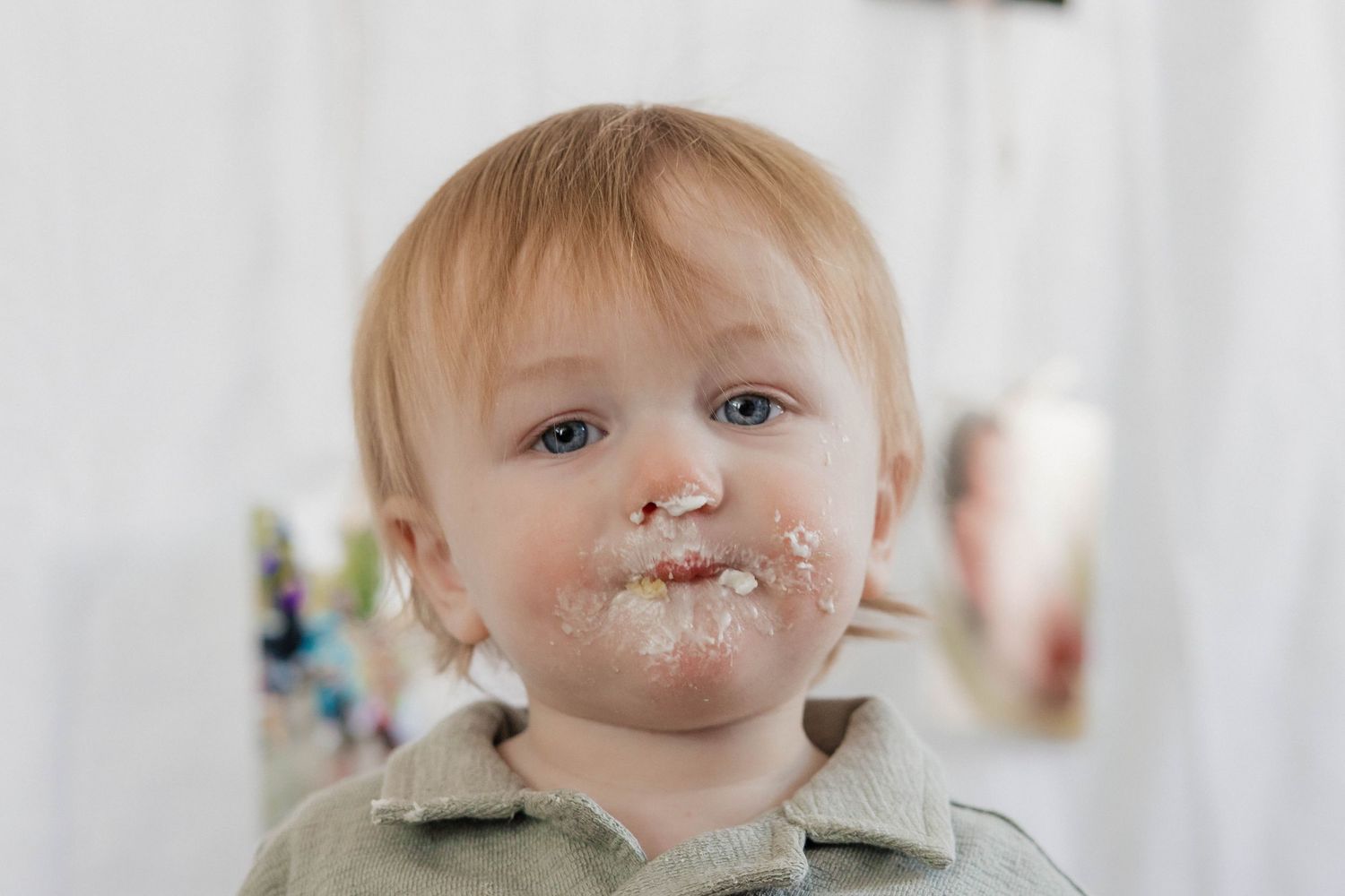 Close-up of toddler with frosting on face after first birthday cake smash session.