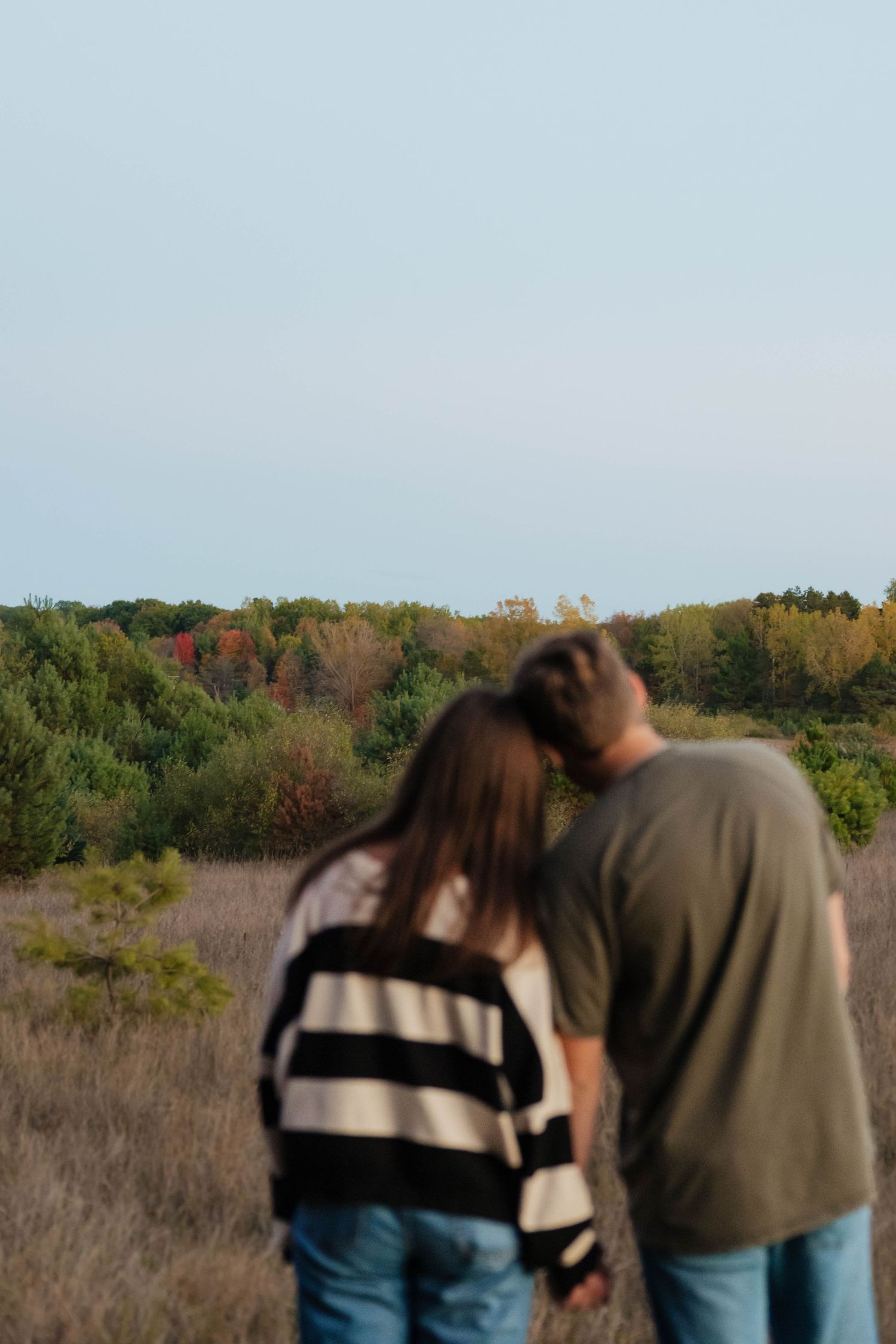 Couple holding hands while looking at a colorful autumn forest landscape.