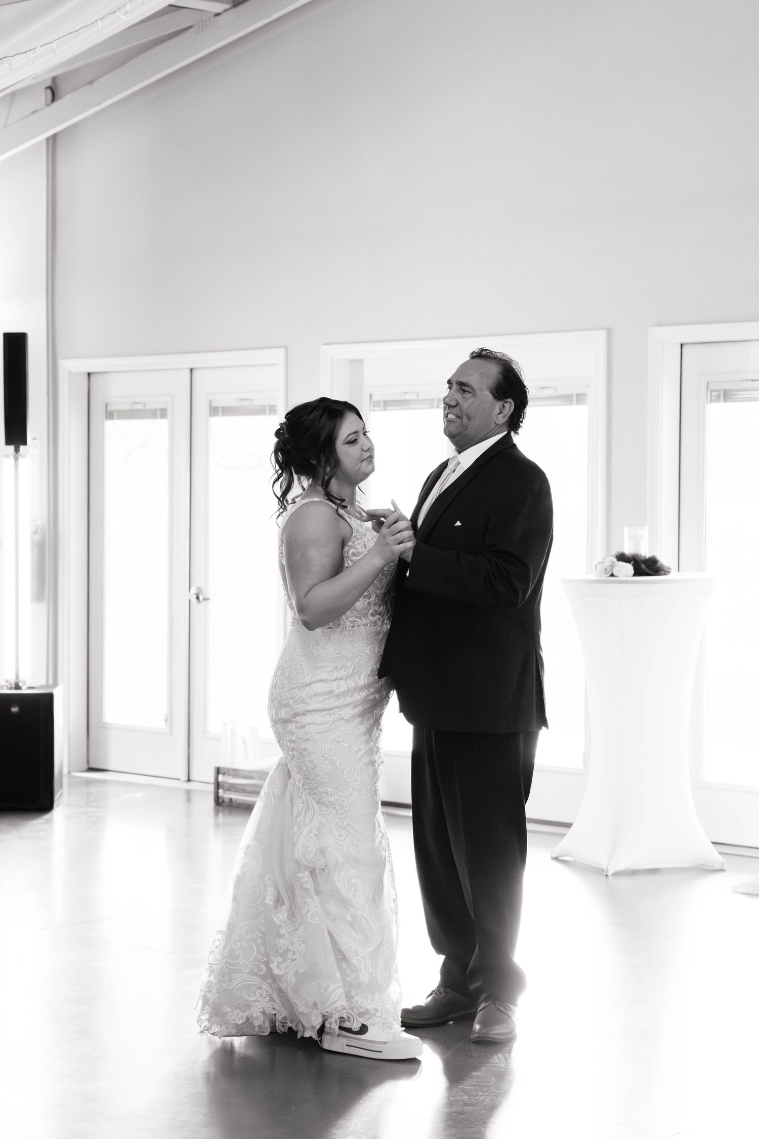 Black and white photo of bride and groom sharing first dance in elegant wedding venue.