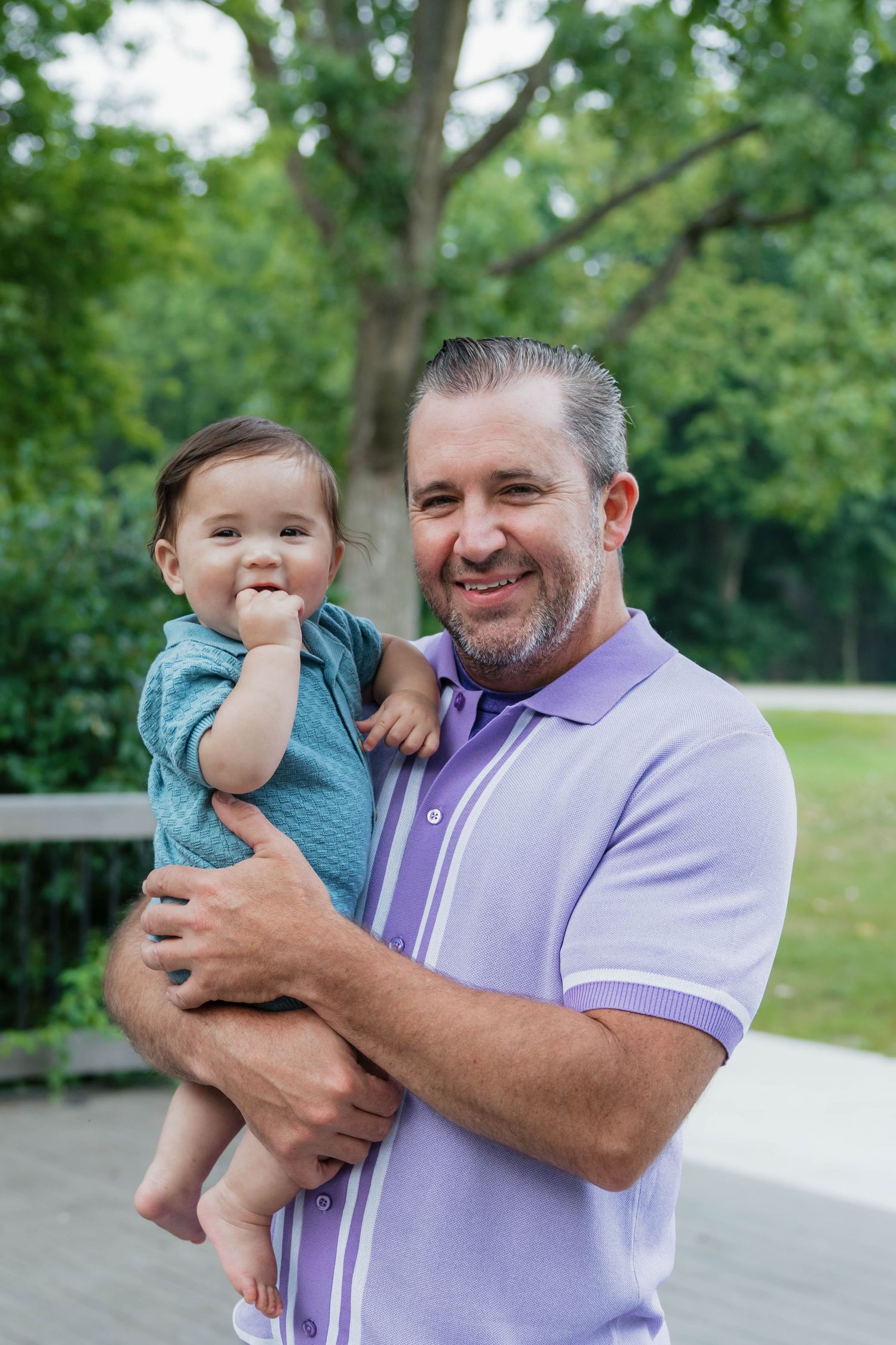 Cheerful father and baby boy sharing a happy moment in a green park.